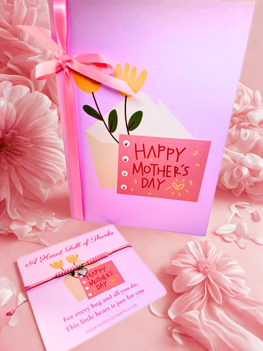 Pink 'Happy Mother's Day' card with flowers and a bow on a pink floral background with matching heart charm bracelet 