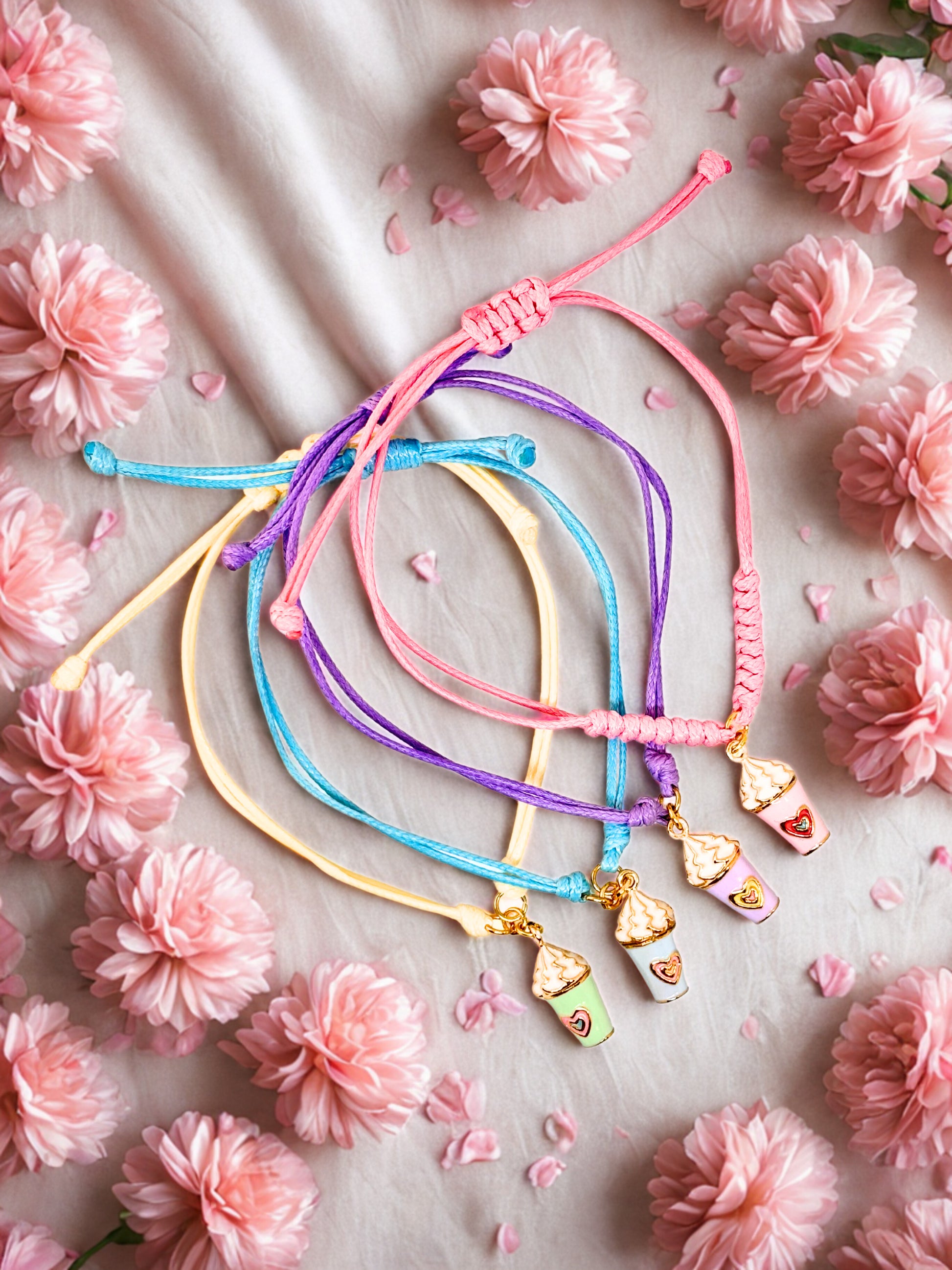 Colorful bracelets with milkshake charms on a floral background