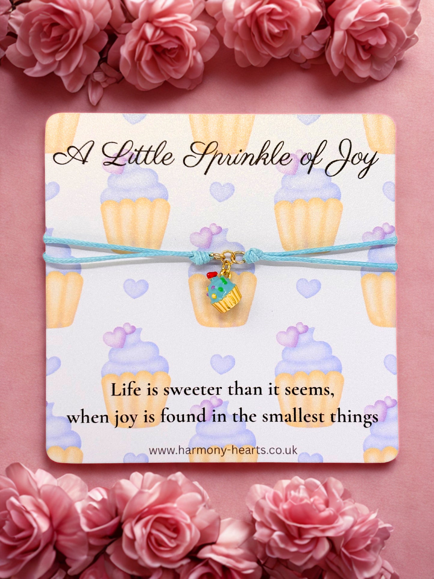Card with cupcake design and cupcake charm bracelet with inspirational quote surrounded by pink flowers on a pink background