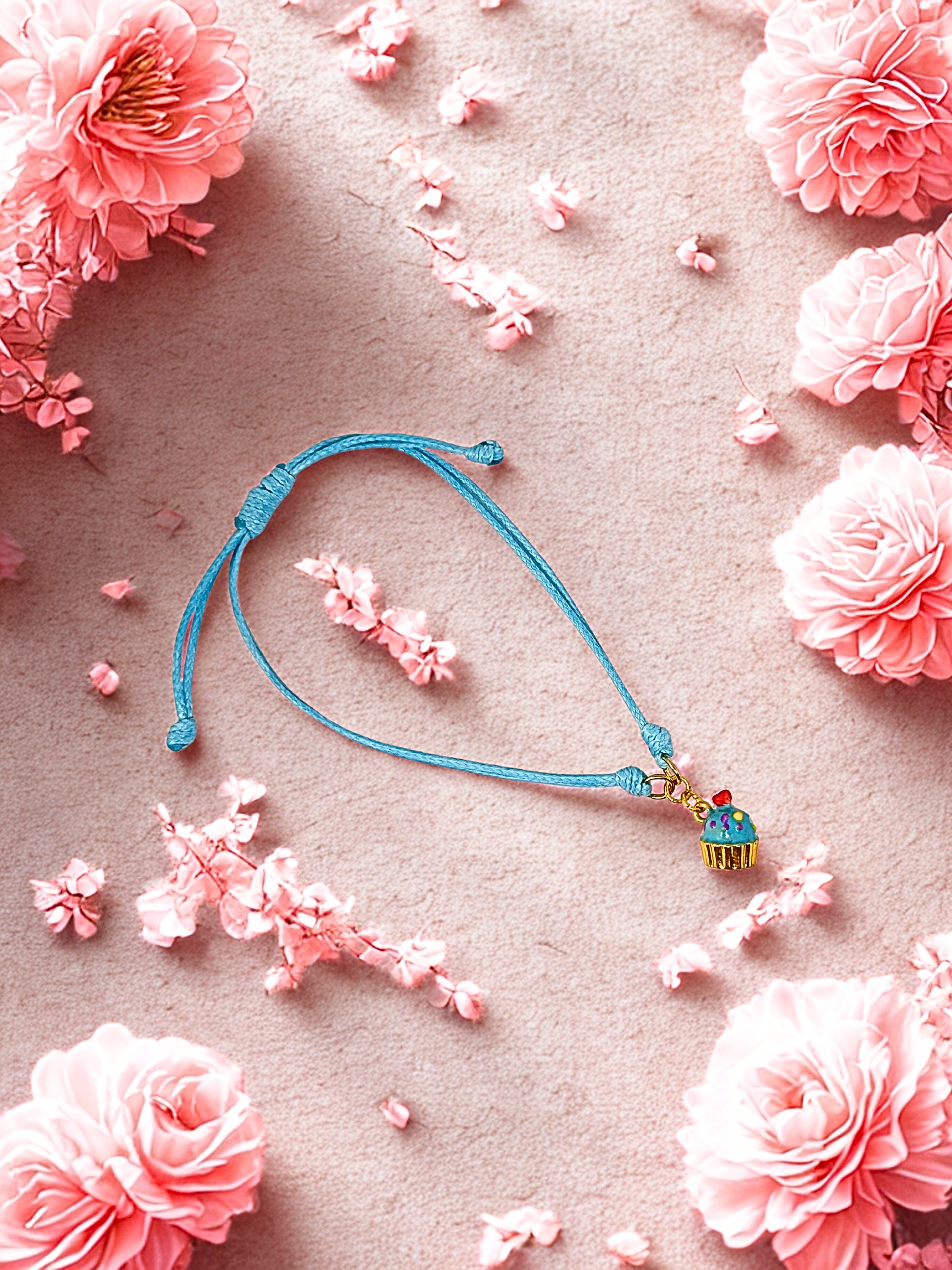 Blue bracelet with a small cupcake charm charm on a pink floral background
