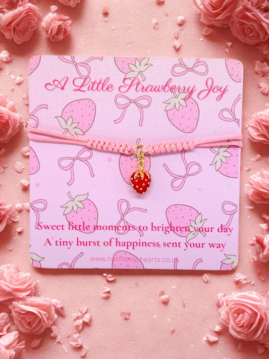 Pink cord bracelet with a strawberry charm presented on a Harmony Hearts branded card
