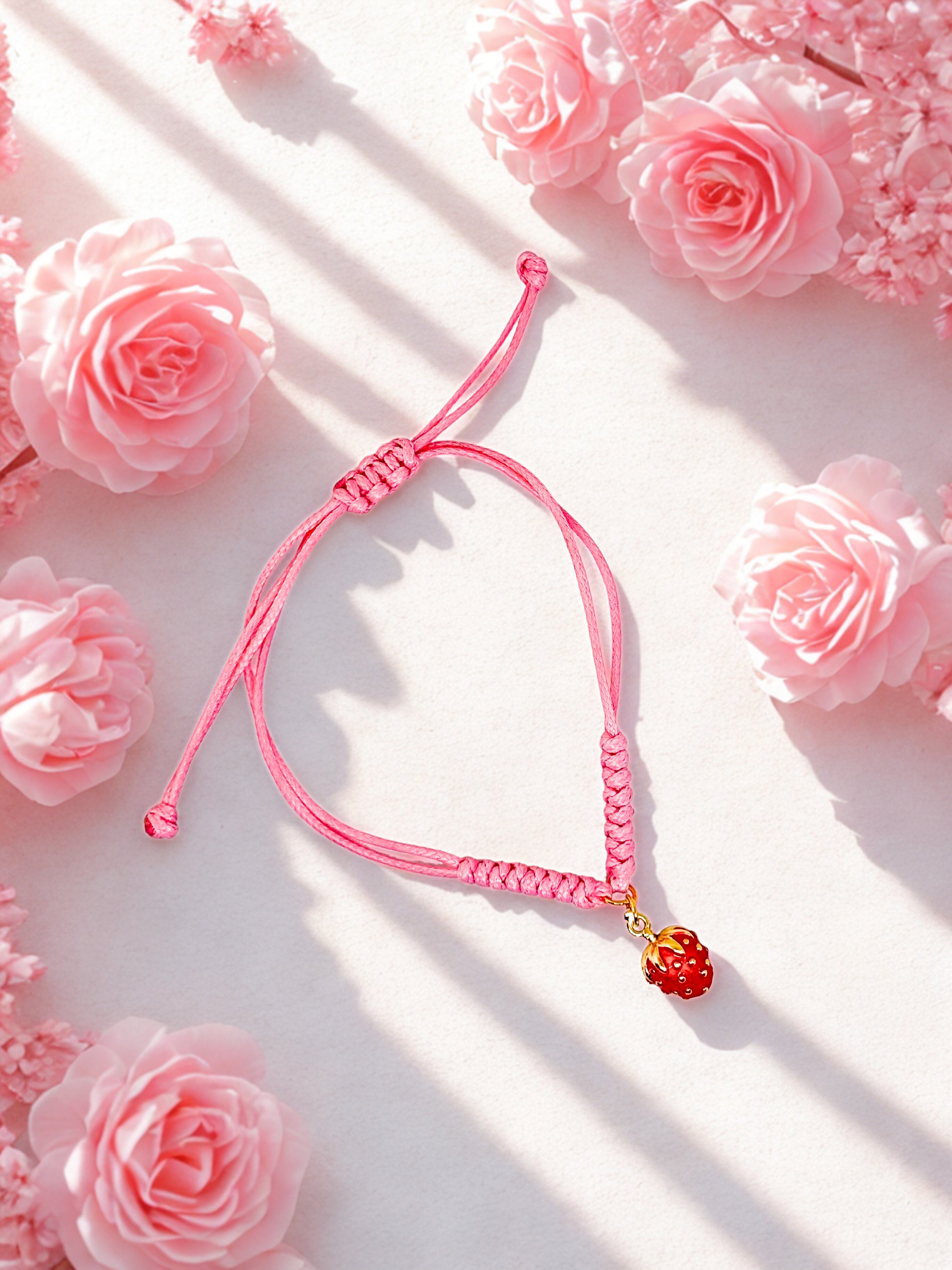 Pink cord bracelet with a red and gold strawberry charm