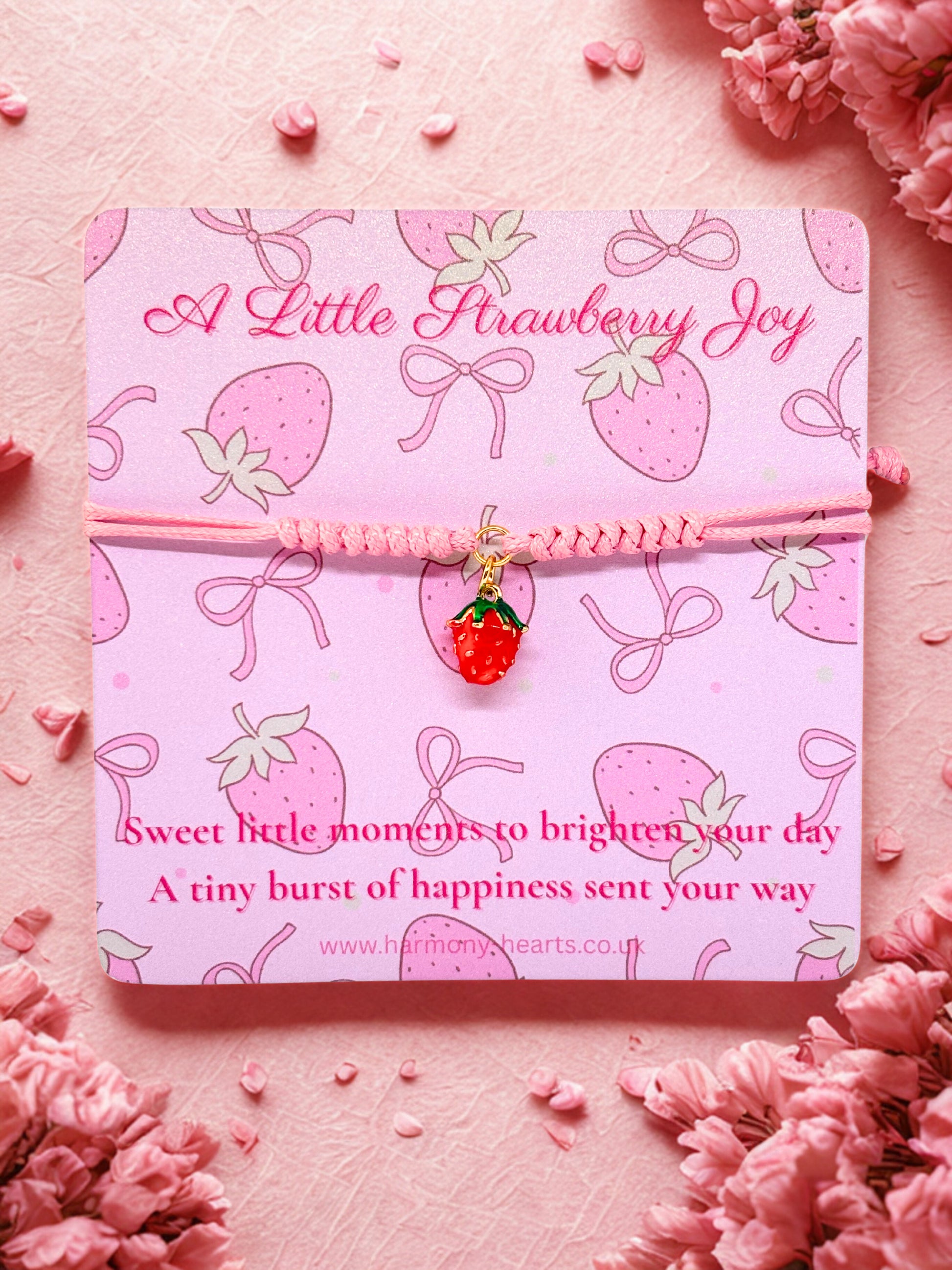 Pink cord bracelet with a strawberry charm presented on a Harmony Hearts branded card