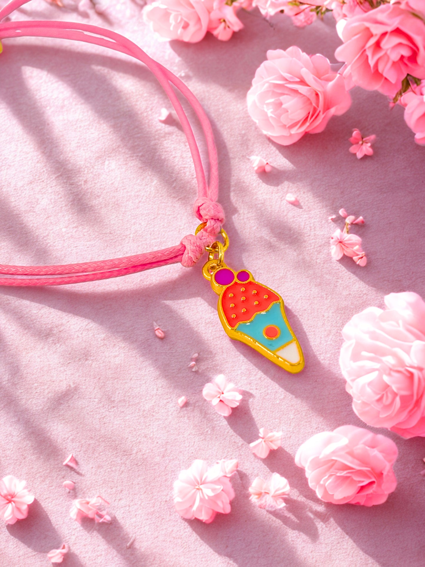 Pink bracelet  with a colorful ice cream charm on a pink floral background