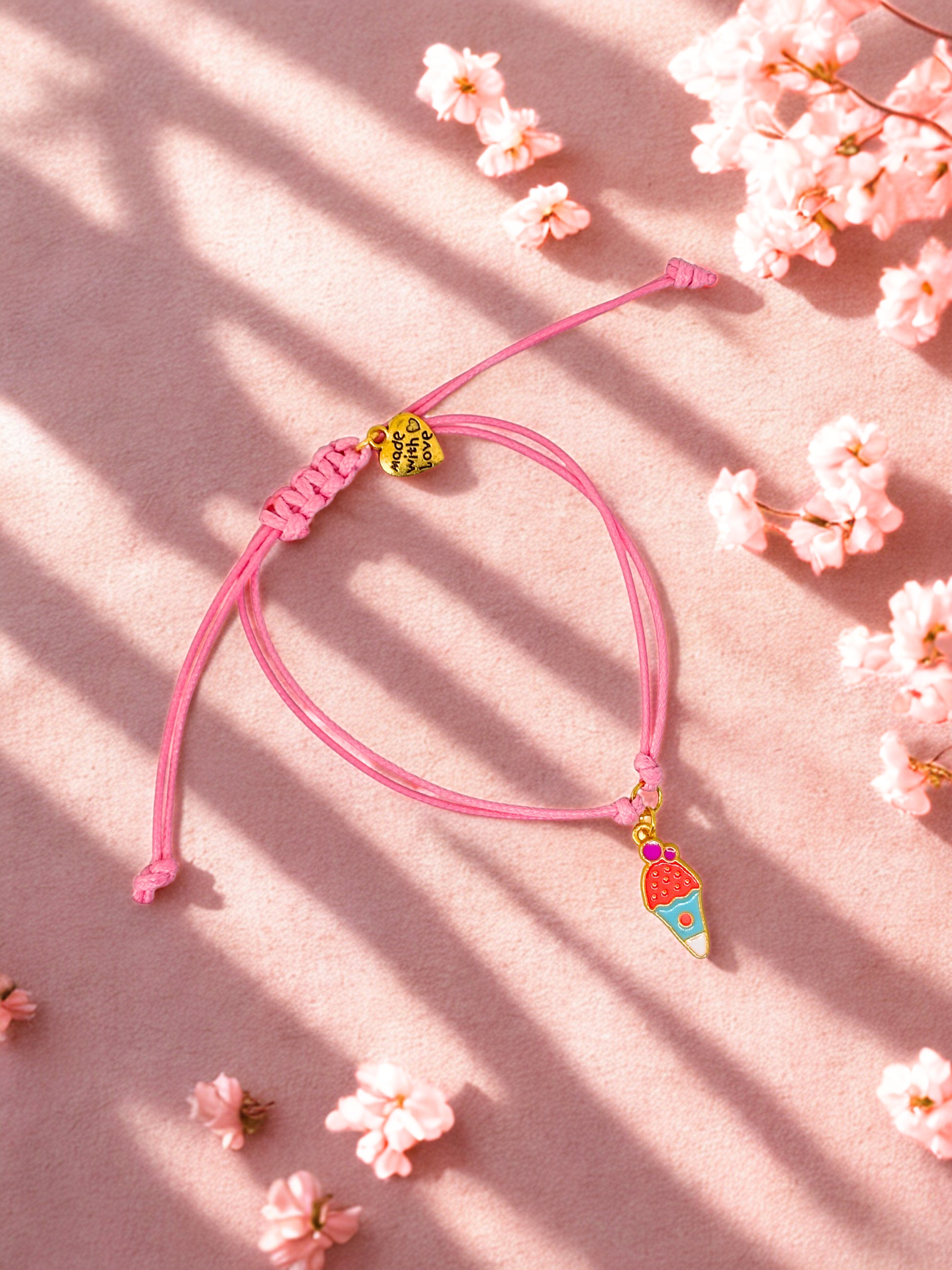 Pink bracelet with colorful ice cream charm on a pink background with flowers