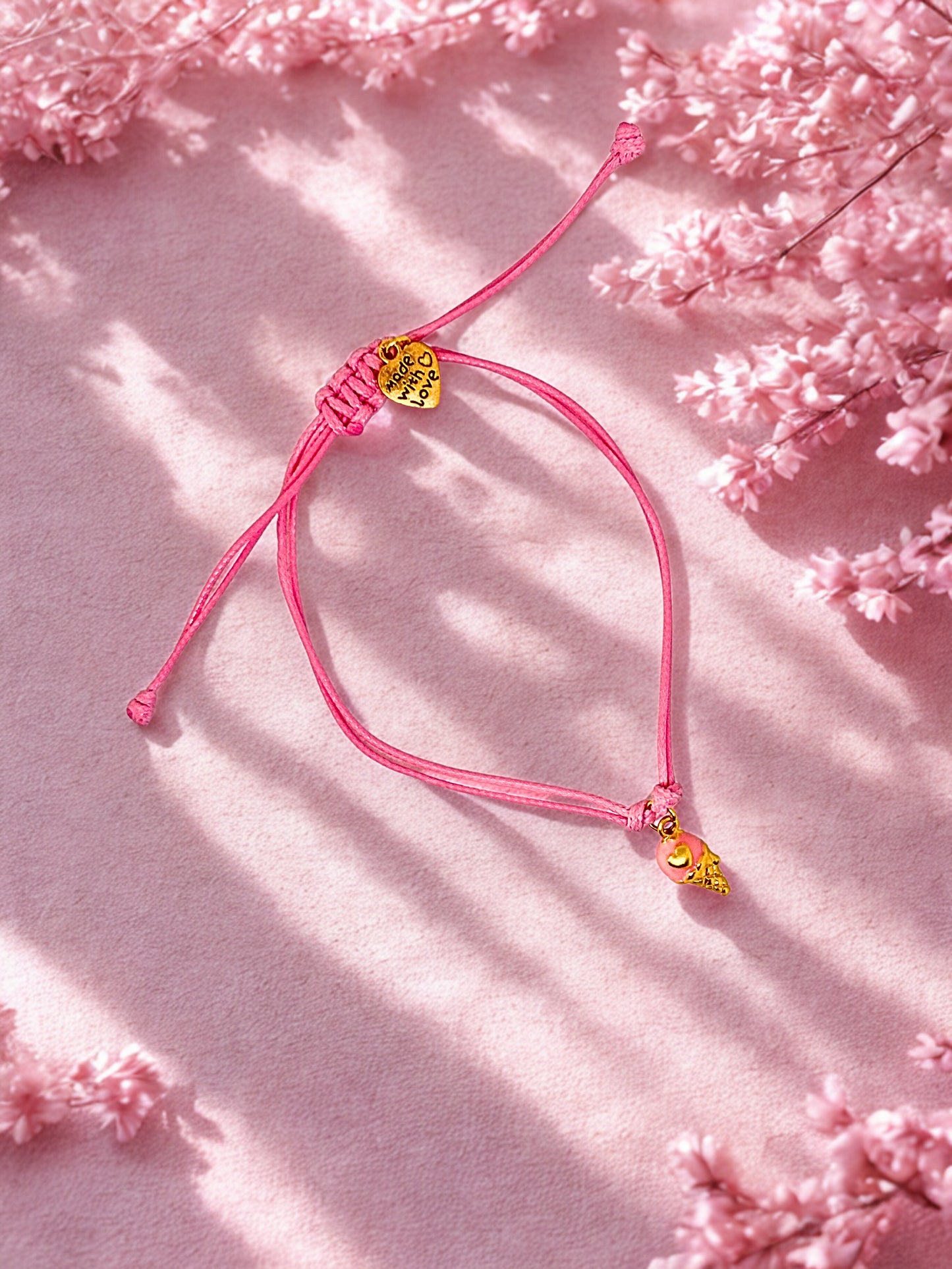 Pink bracelet with ice cream charm on a pink floral background