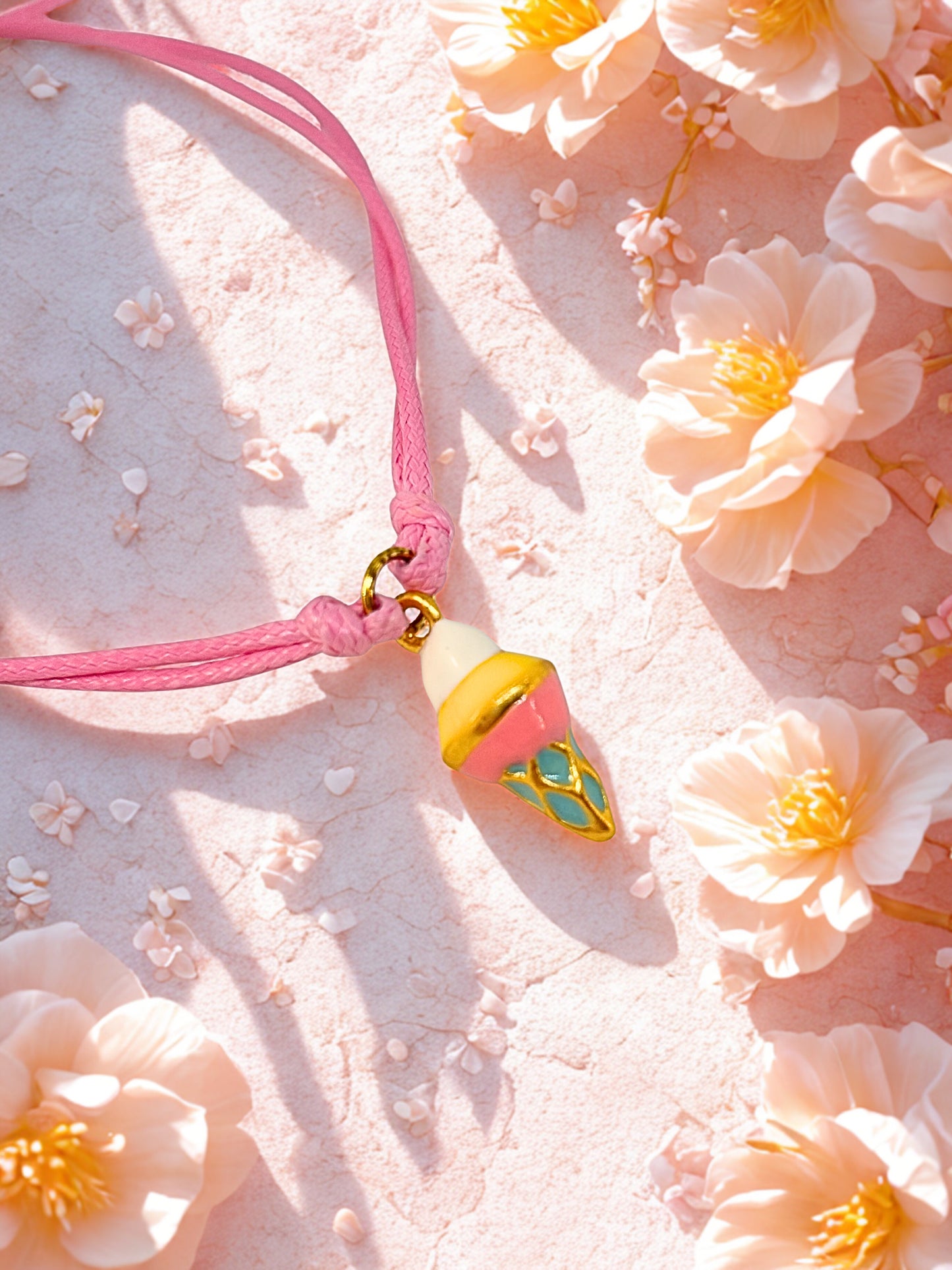 Pink charm bracelet with a decorative ice cream charm on a pink floral background