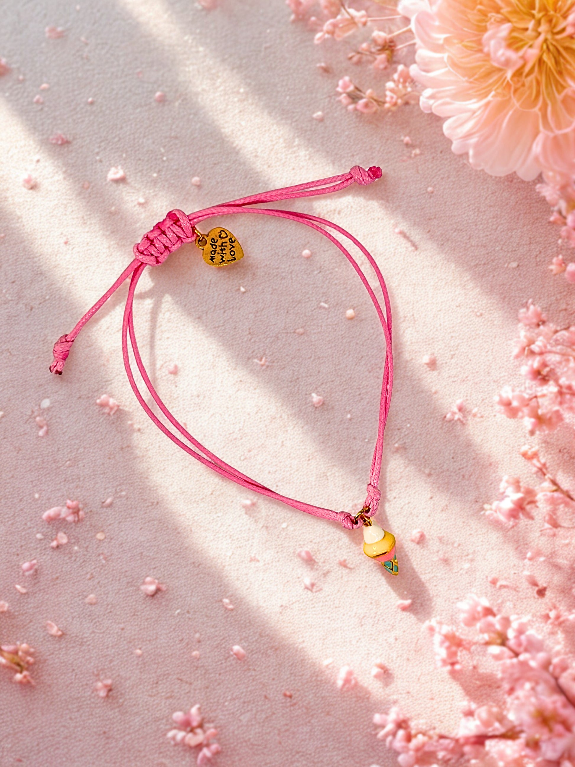 Pink bracelet with an ice cream charm on a pink floral background