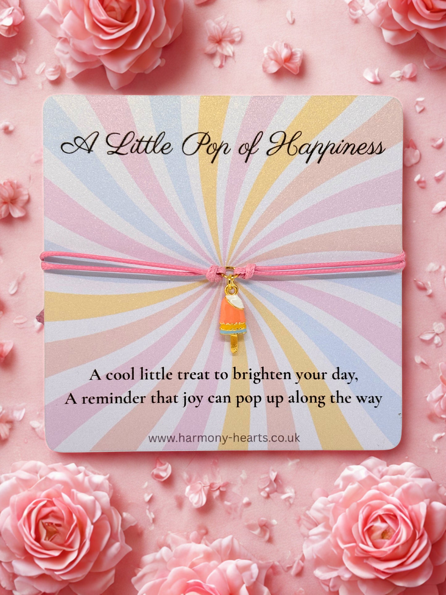 Decorative card with sunburst pattern and pink ice lolly charm bracelet on a pink floral background