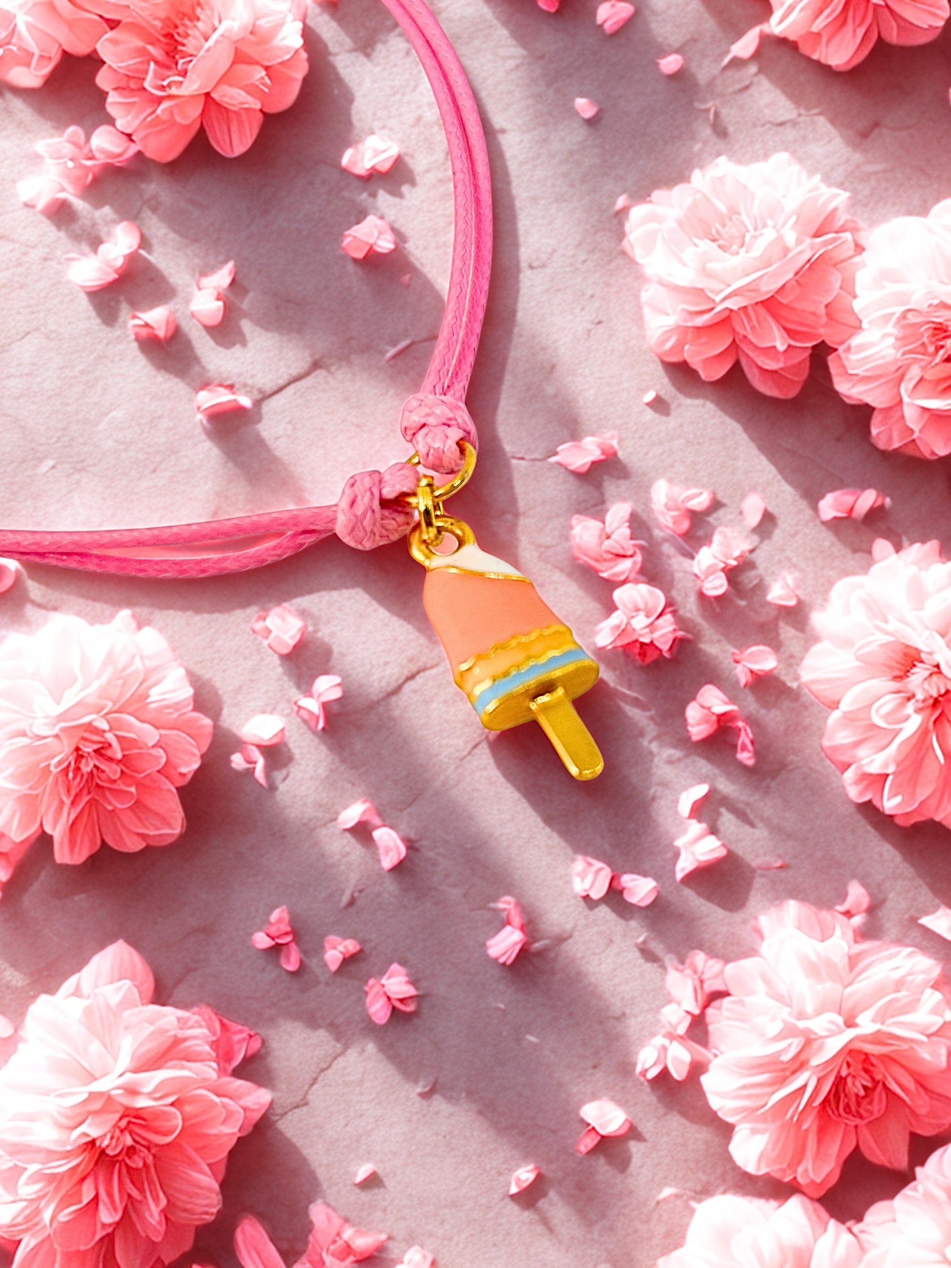 Bracelet with an ice lolly charm on a pink floral background