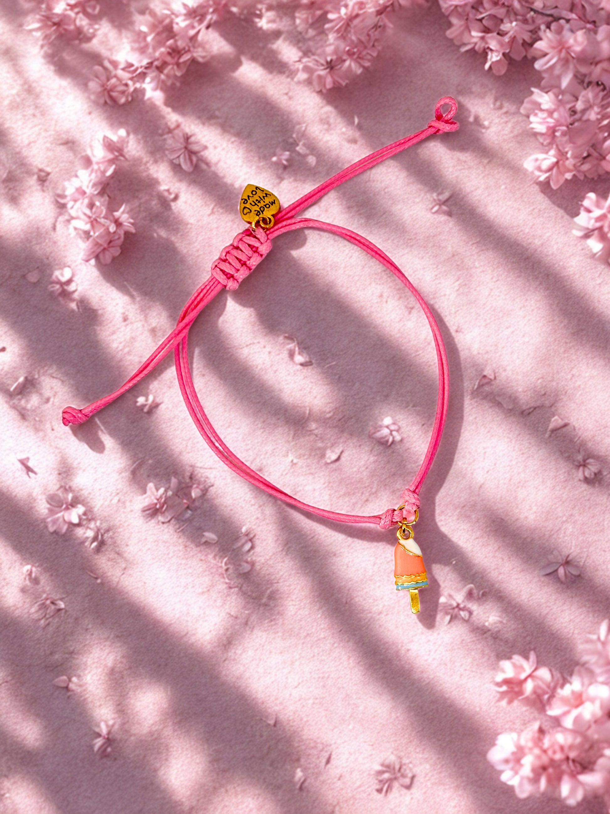 Pink bracelet with an ice lolly charm on a pink floral background