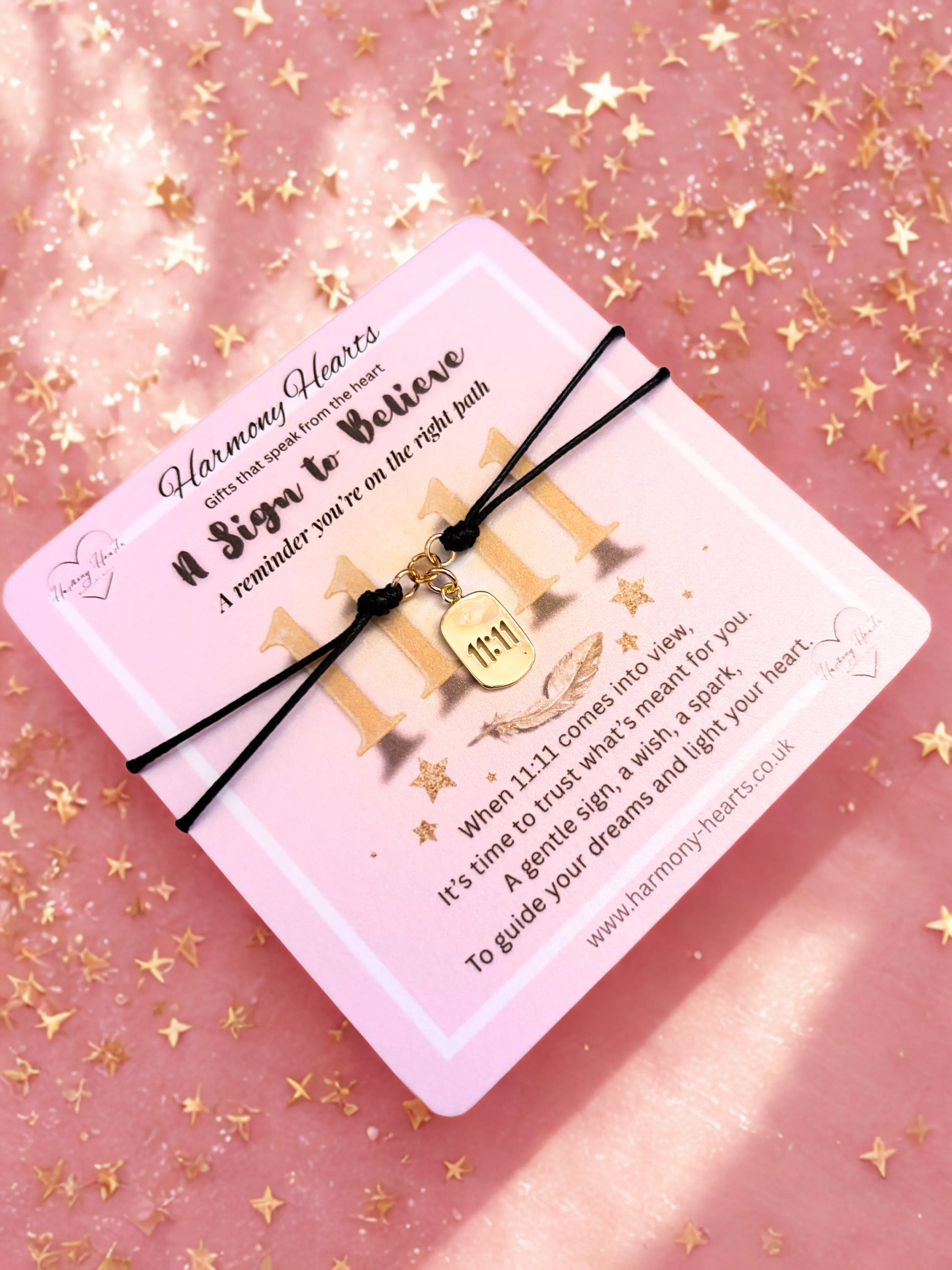 Gold 1111 charm bracelet on pink poem card against a pink background with gold stars