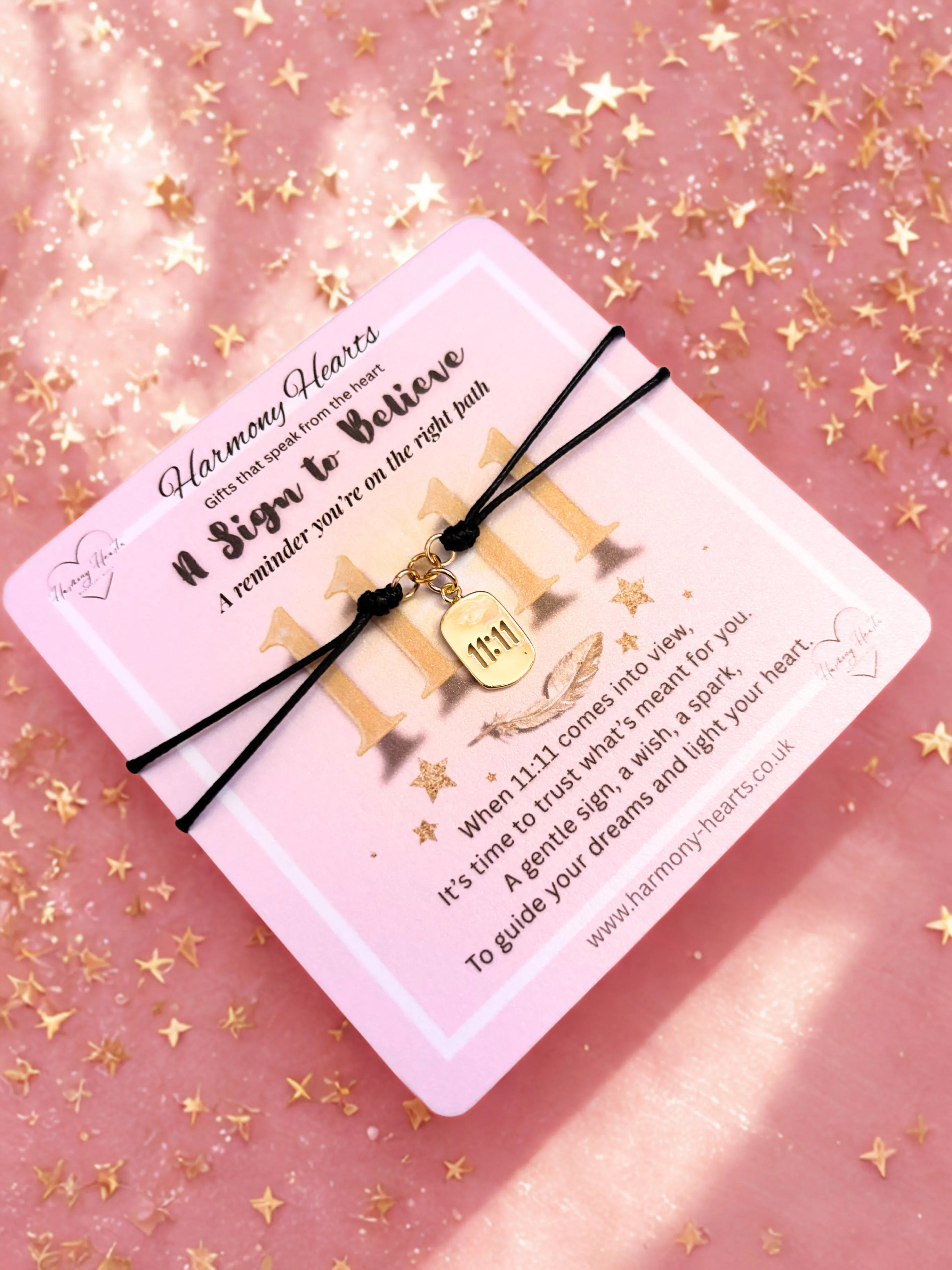 Gold 1111 charm bracelet on pink poem card against a pink background with gold stars