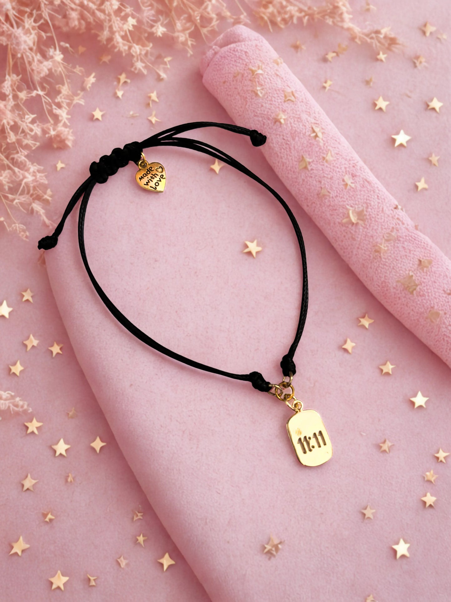 Gold 1111 charm bracelet laid on a pink surface with stars