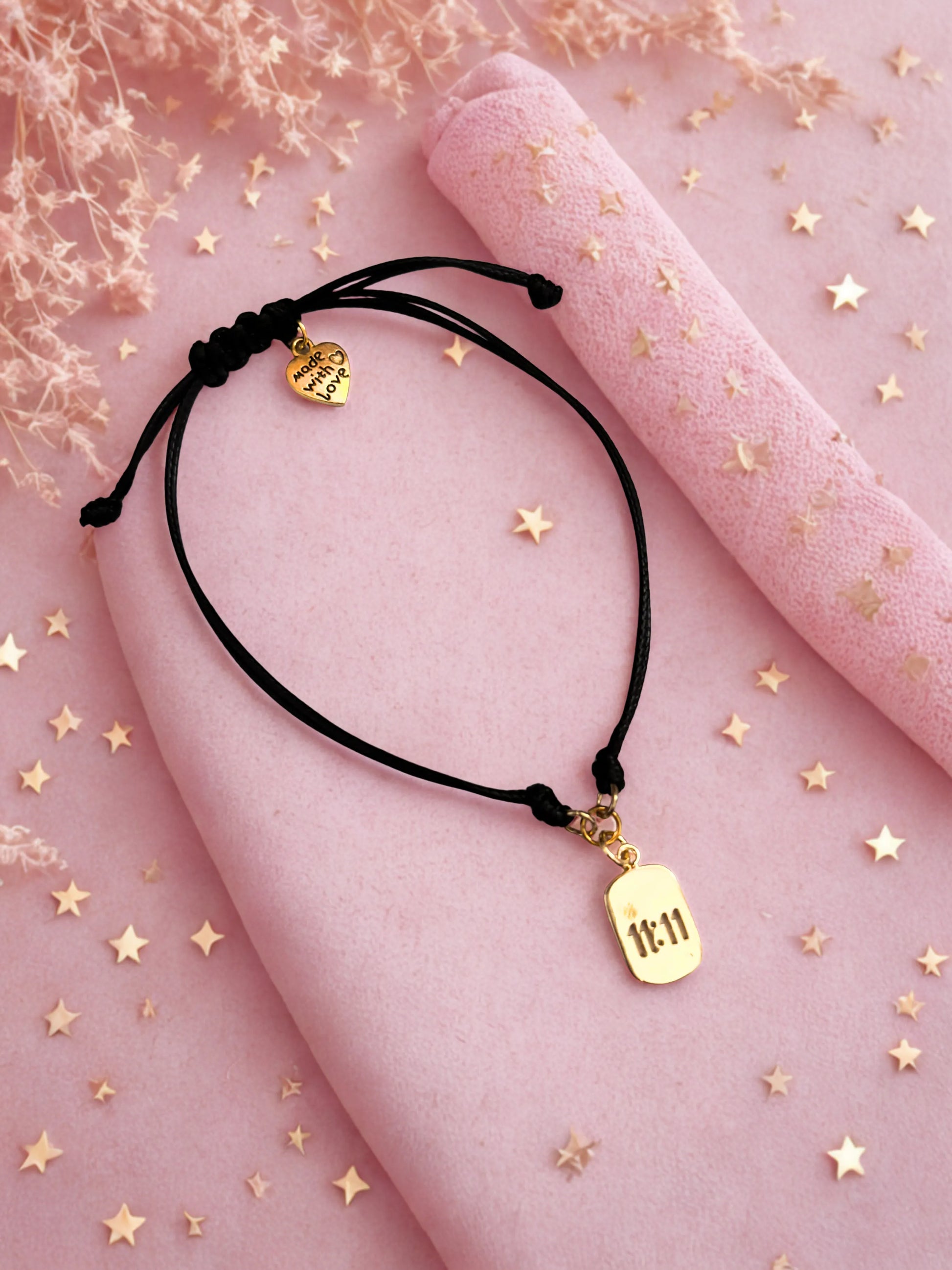 Gold 1111 charm bracelet laid on a pink surface with stars