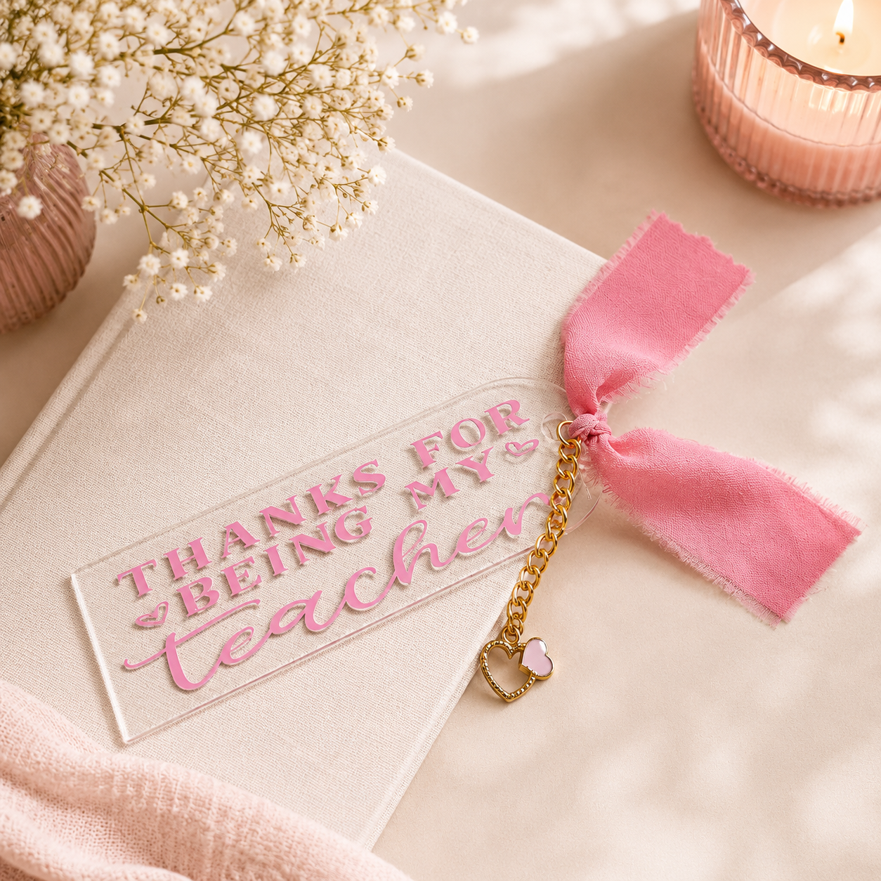 Decorative bookmark with 'Thanks for being my teacher' message, pink ribbon, and heart charm on a soft background.