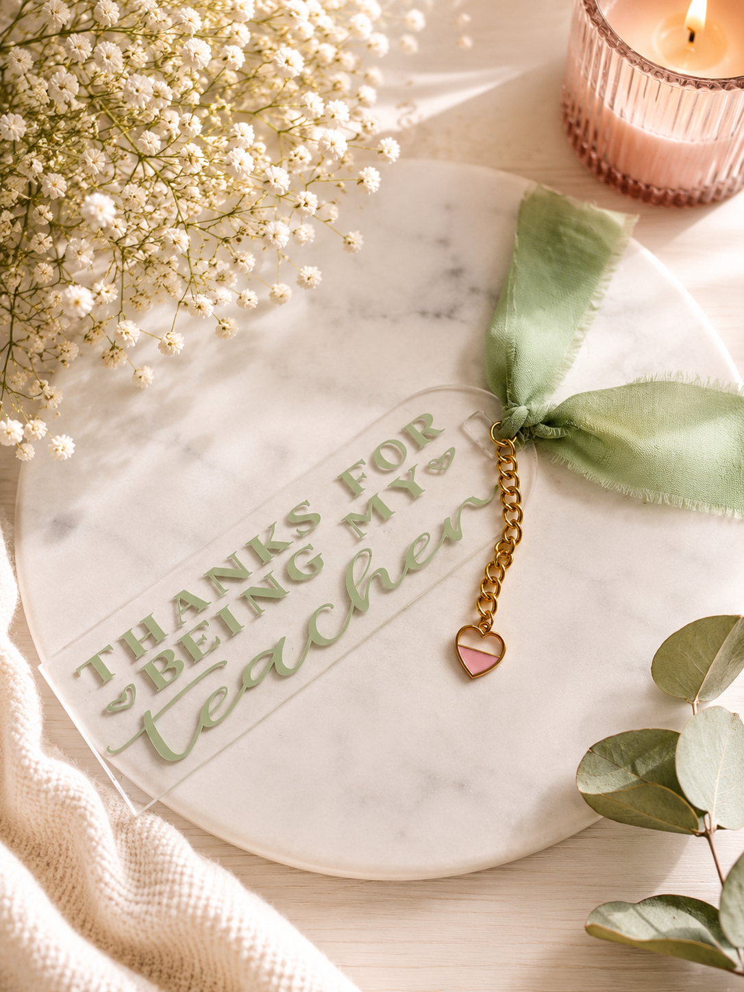 Acrylic bookmark with 'Thanks for being my teacher' text, heart charm, and green ribbon on a light background.