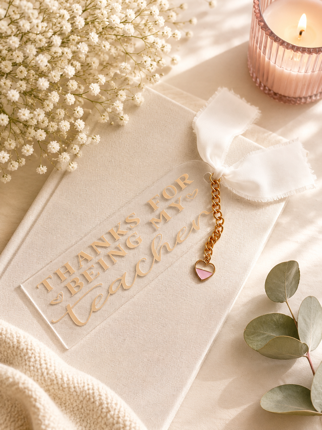 Acrylic bookmark with heart charm with 'Thanks for being my teacher' text, surrounded by flowers and a candle.