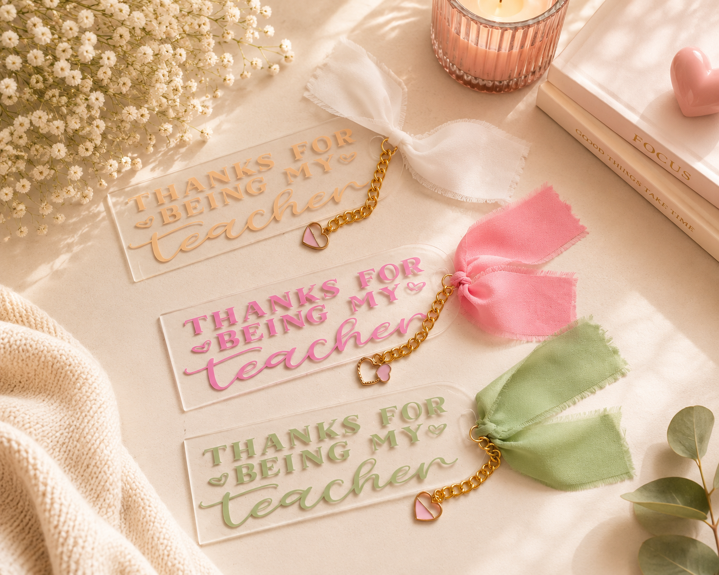 Three 'Thanks for being my teacher' bookmarks with decorative ribbons on a soft surface.