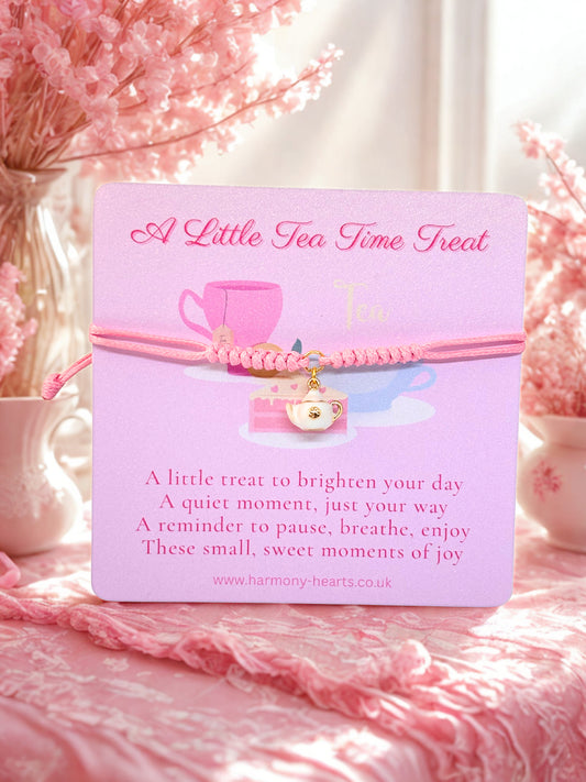 Pink cord bracelet with a teapot charm presented on a Harmony Hearts branded card and tea cup illustration, surrounded by pink flowers.