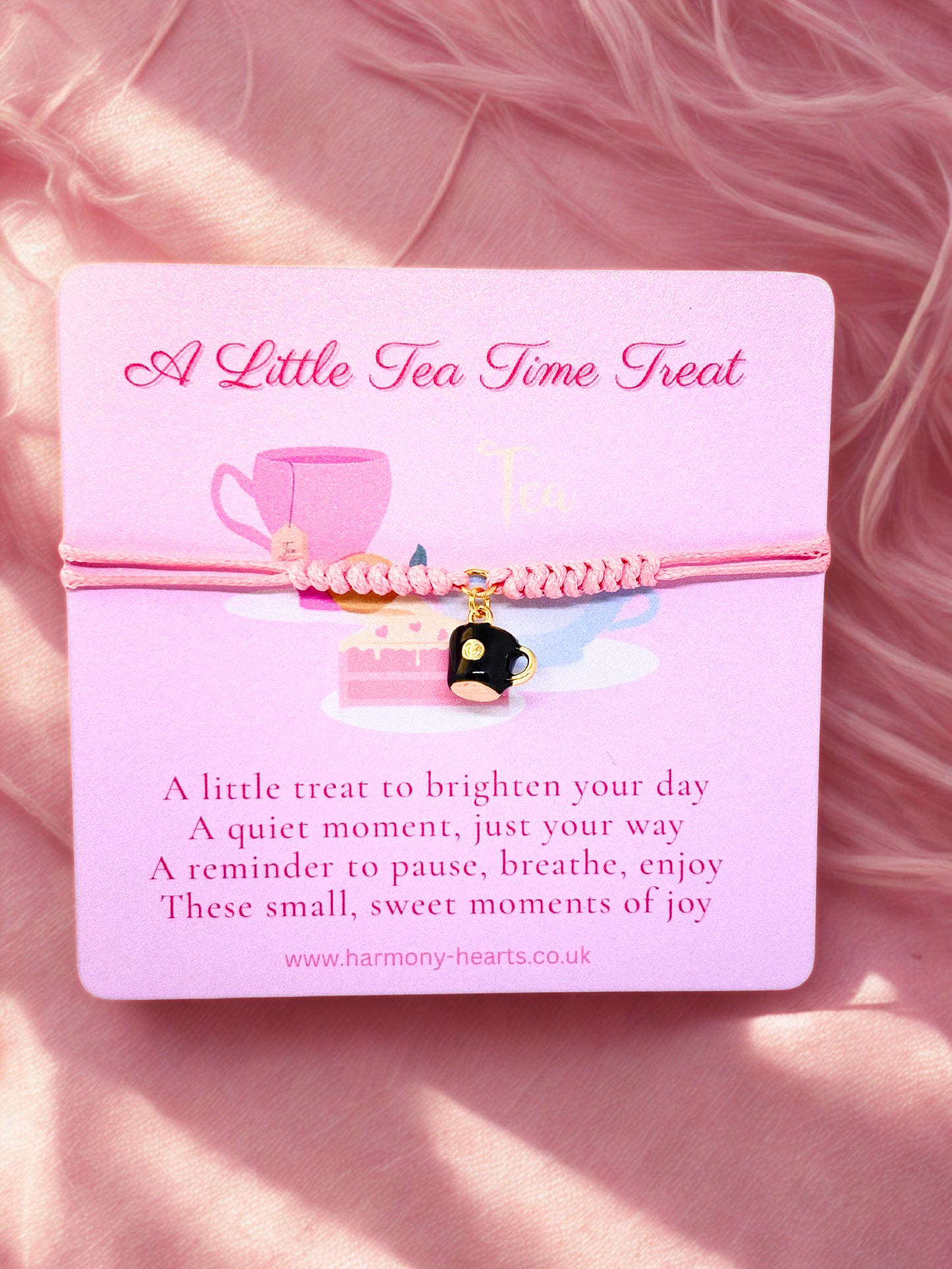 Pink card with a pink bracelet and cup charm on a pink fluffy background