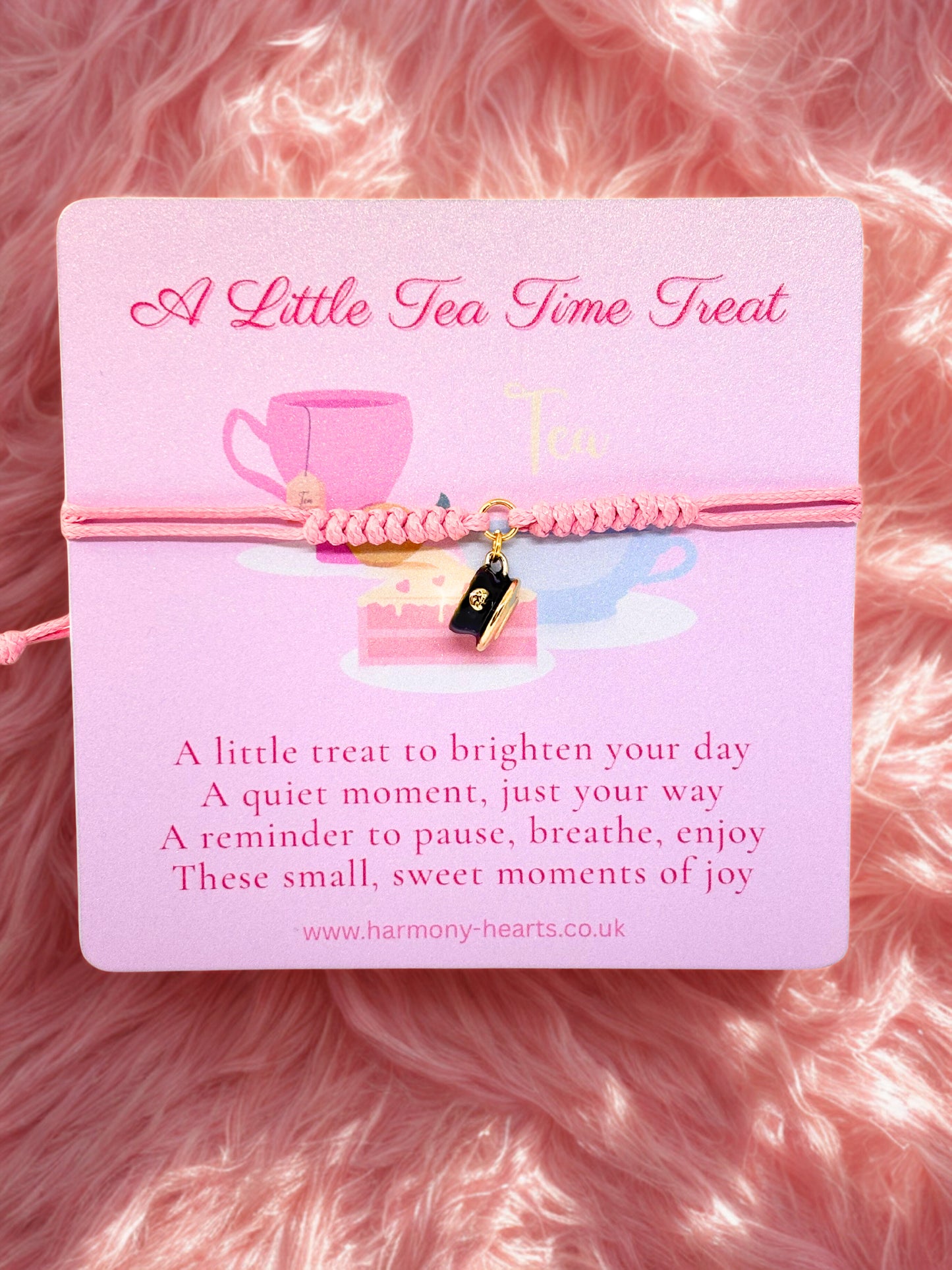 Pink card with a pink bracelet and cup and saucer charm bracelet on a pink fluffy background