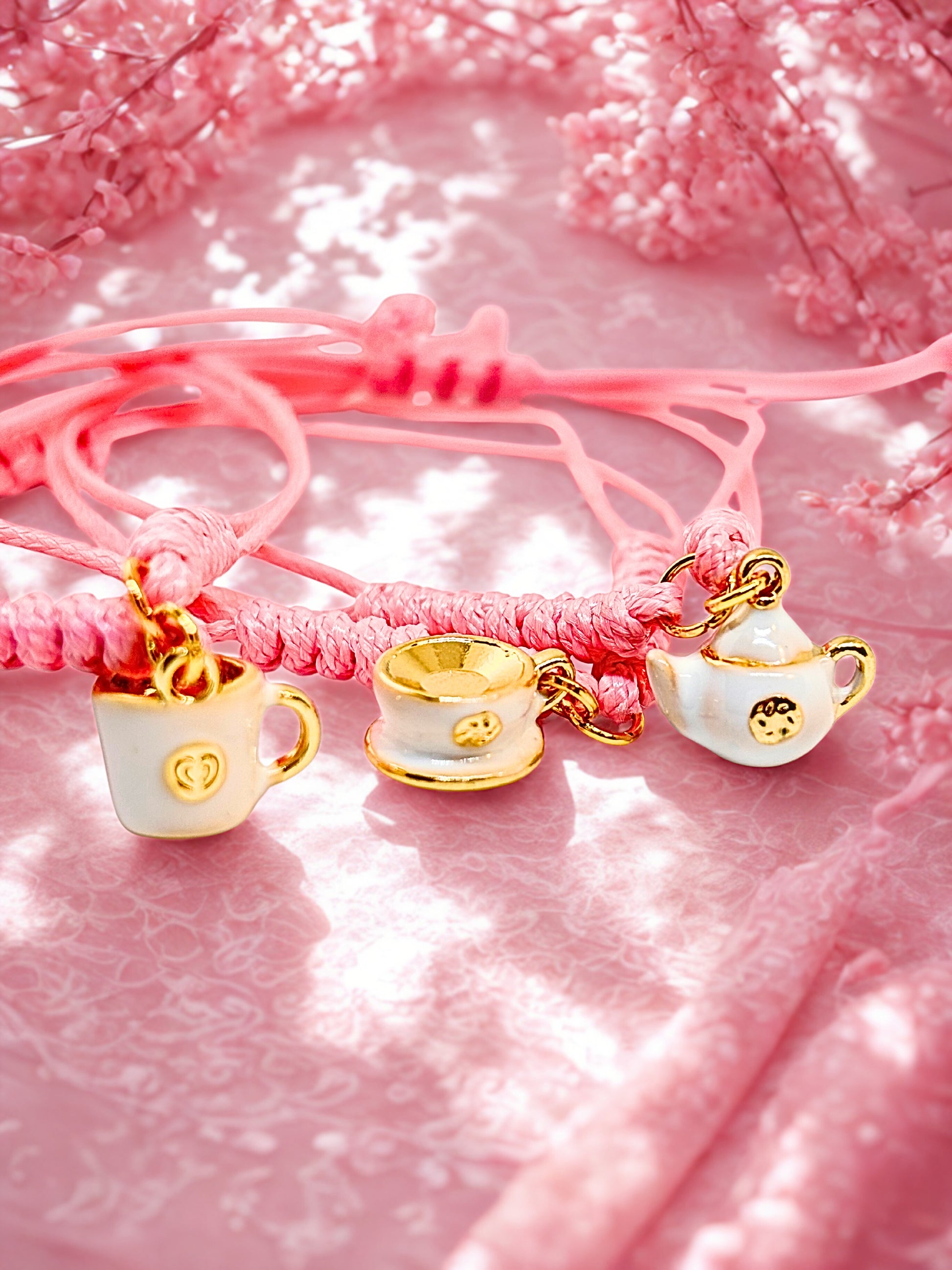 Bracelet with tea cup and teapot charms on a pink background