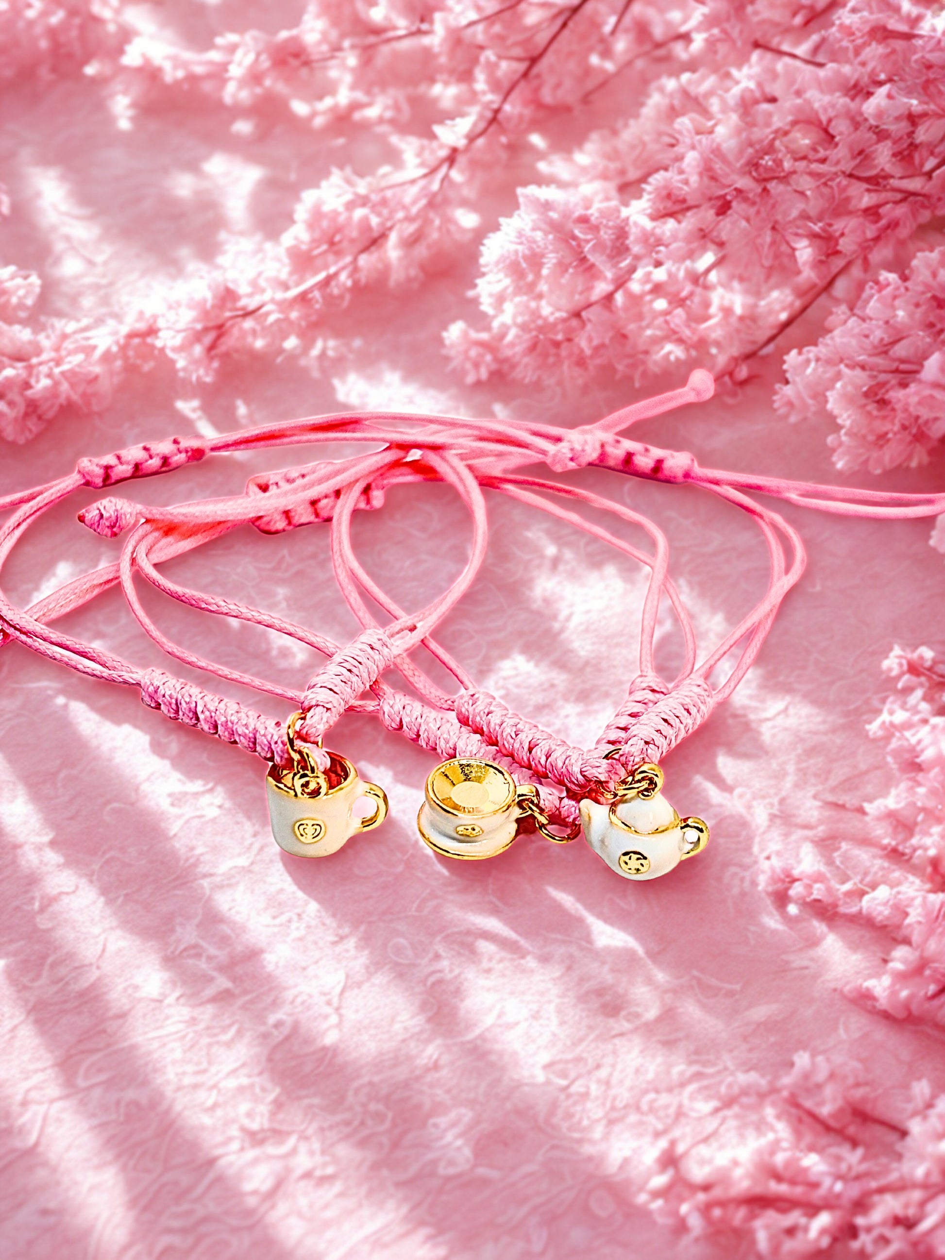 Pink bracelets with teapot and cup  charms on a pink floral background