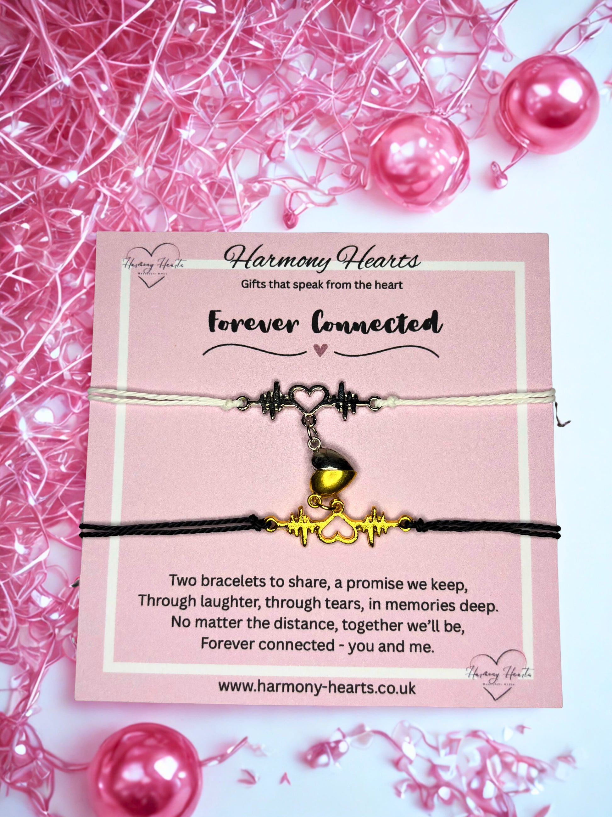 Two bracelets on a pink card with 'Harmony Hearts' branding, surrounded by pink beads and ribbons.
