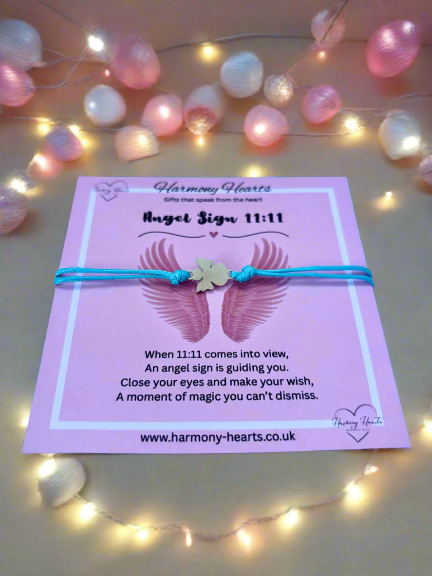 Pink card with angel wings and a string of lights on a light background