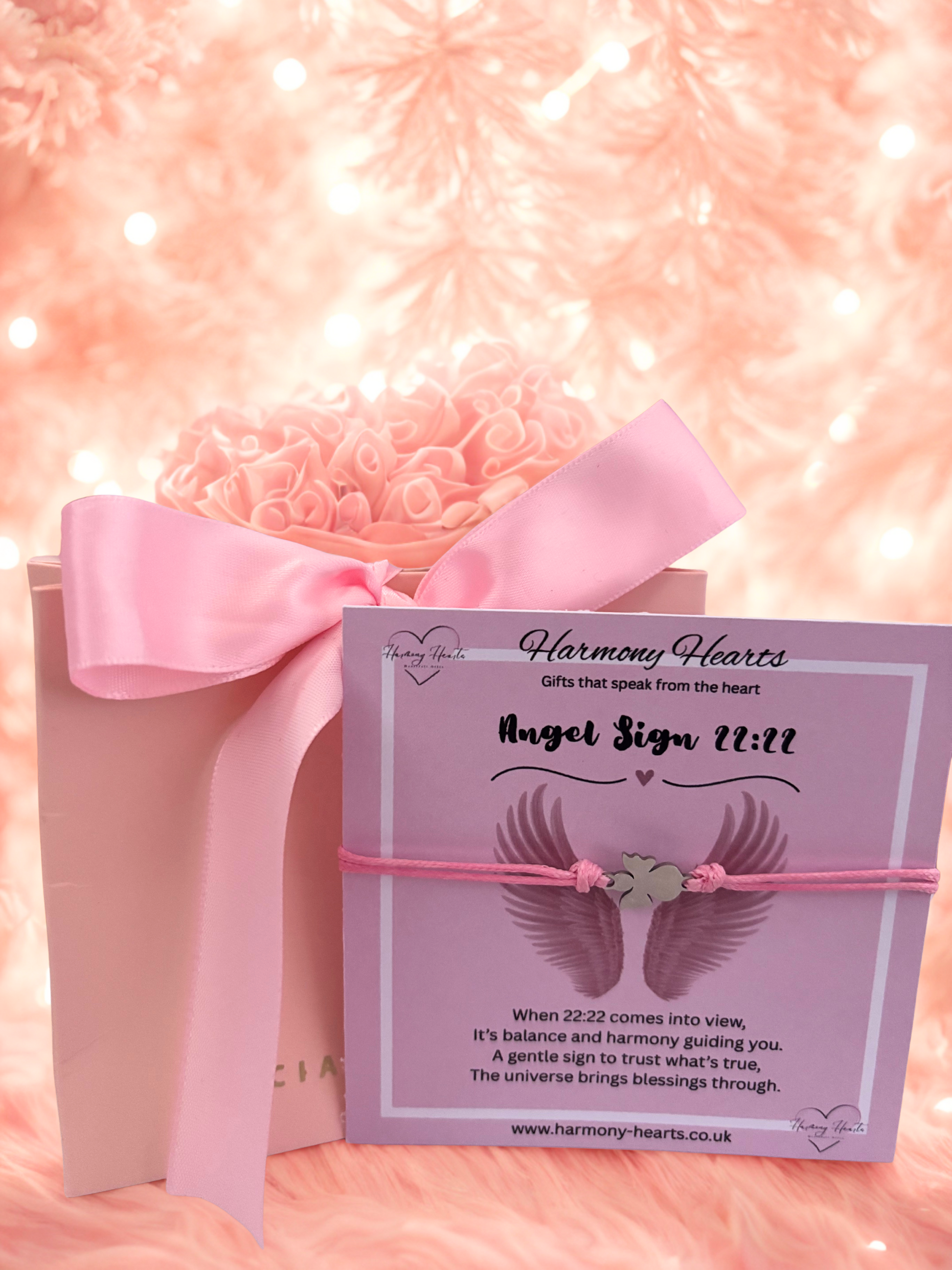 Gift box with pink ribbon and 'Harmony Hearts' card on a soft pink background