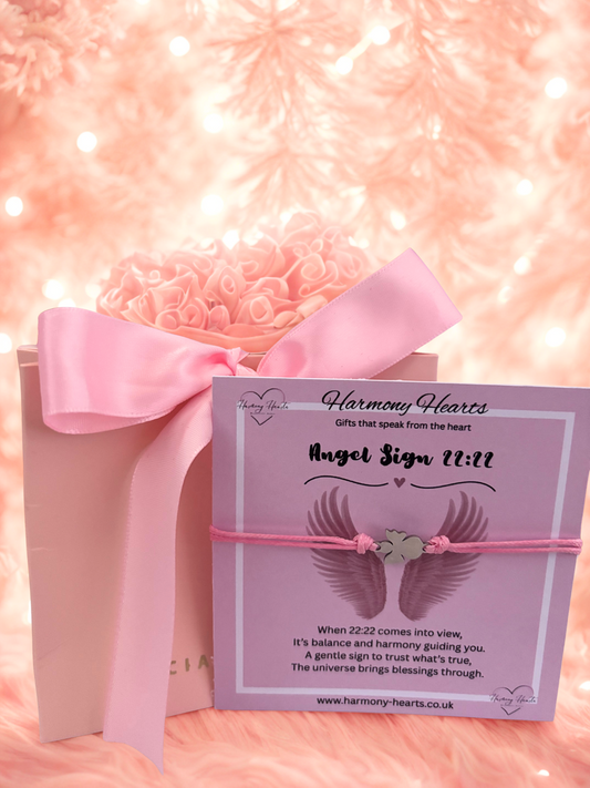 Gift box with pink ribbon and 'Harmony Hearts' card on a soft pink background
