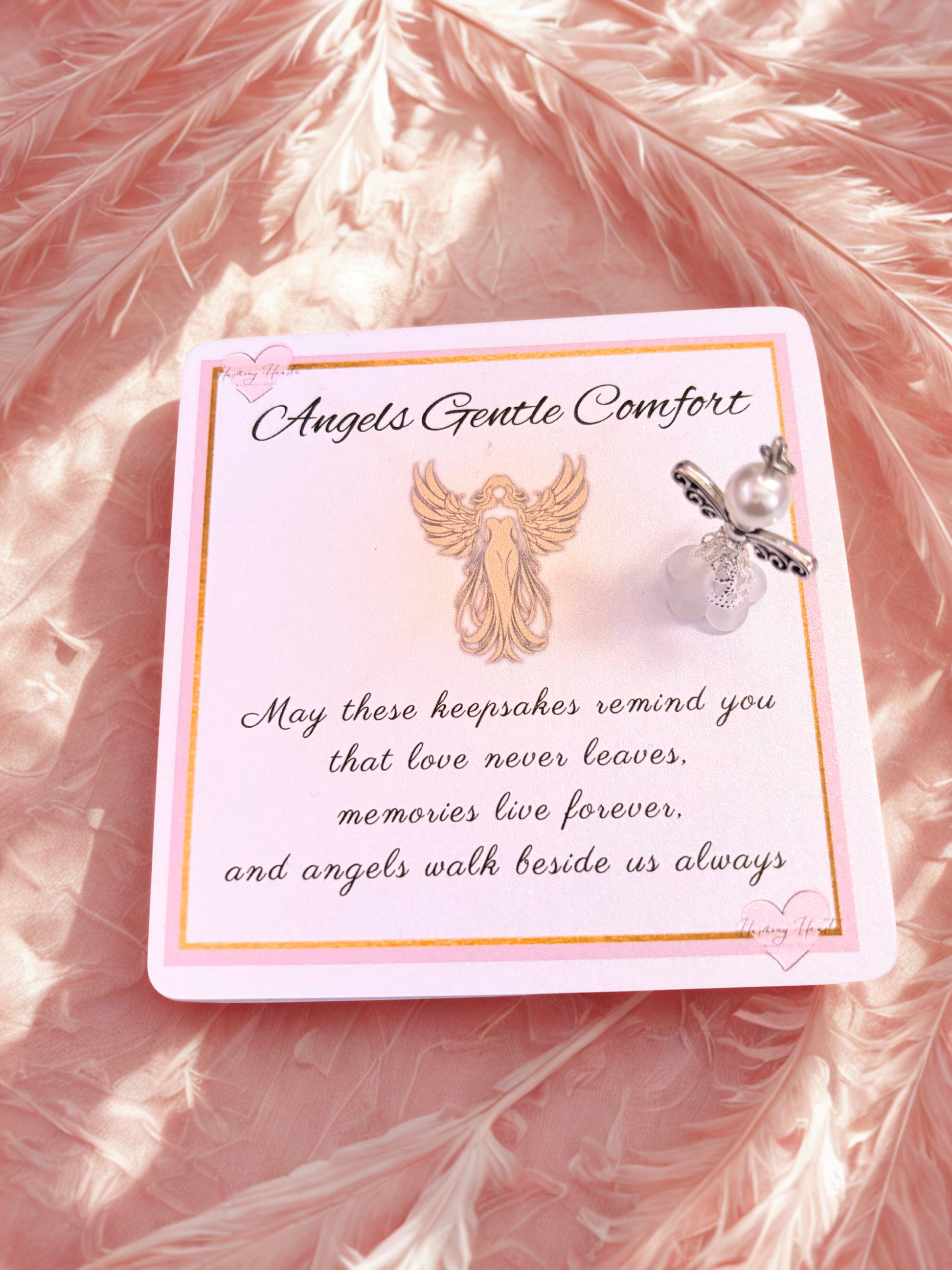 Decorative card with angel wings and heart charm on a pink feather background