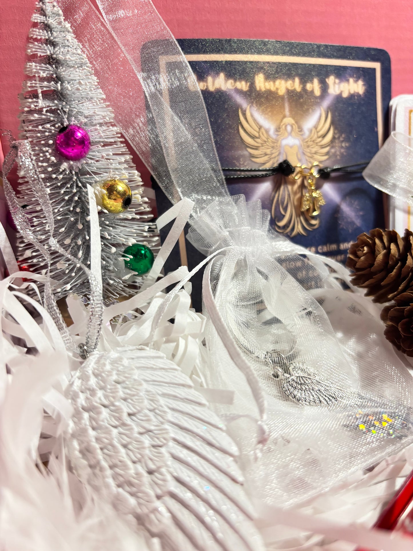 Decorative item with ribbons, feathers, and colorful beads on a pink background