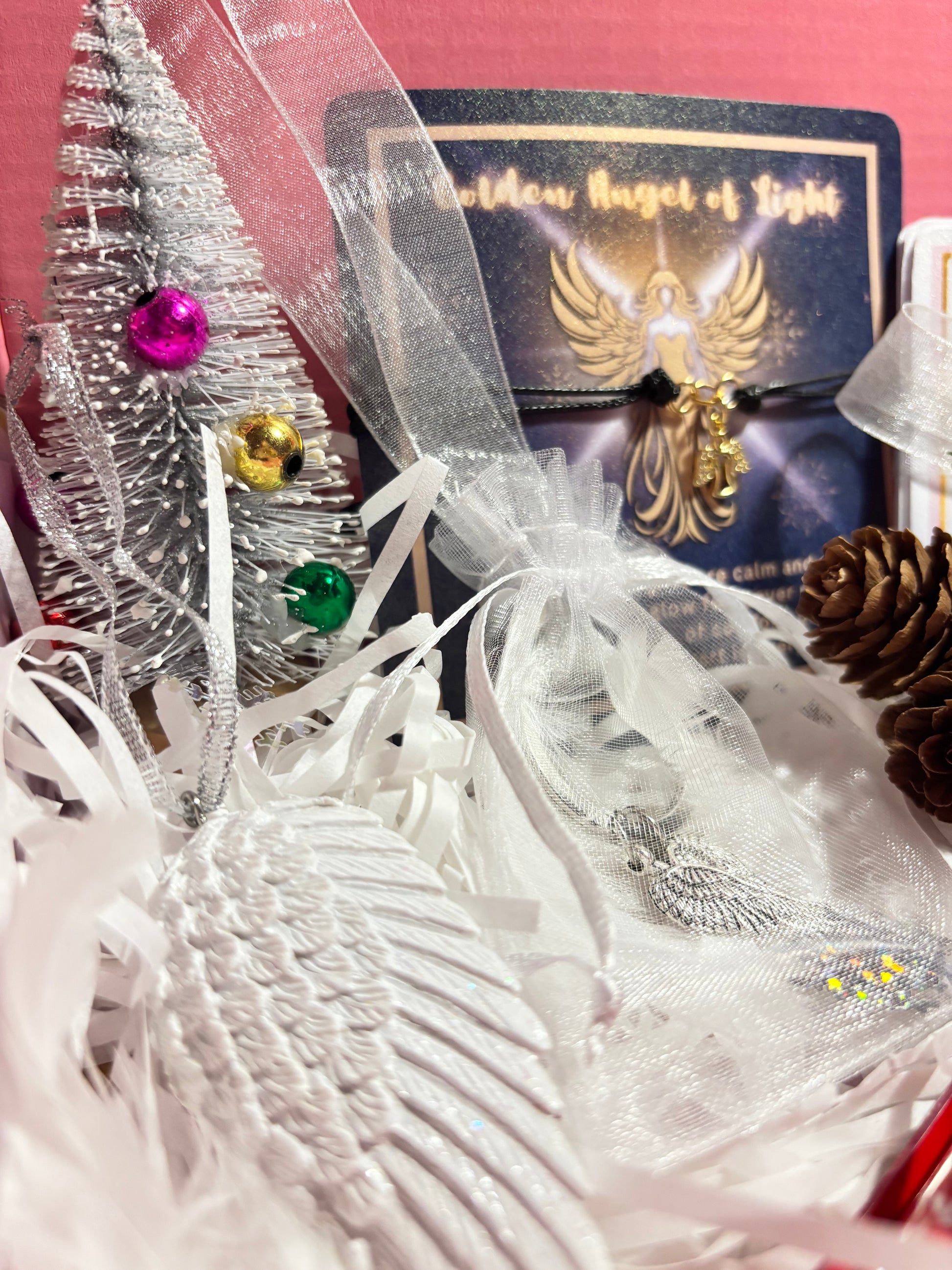 Decorative item with ribbons, feathers, and colorful beads on a pink background