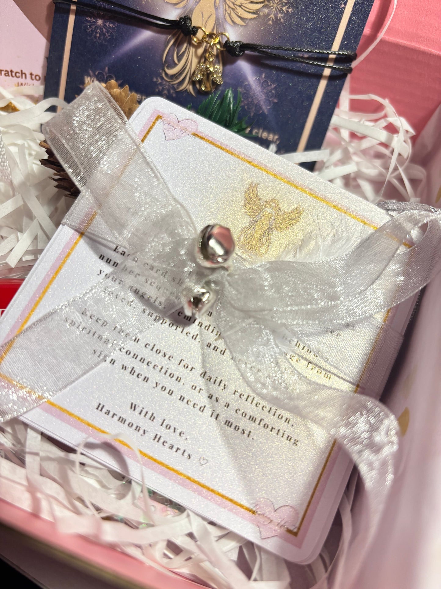 Decorative card with a silver bow and text, placed on a pink box.