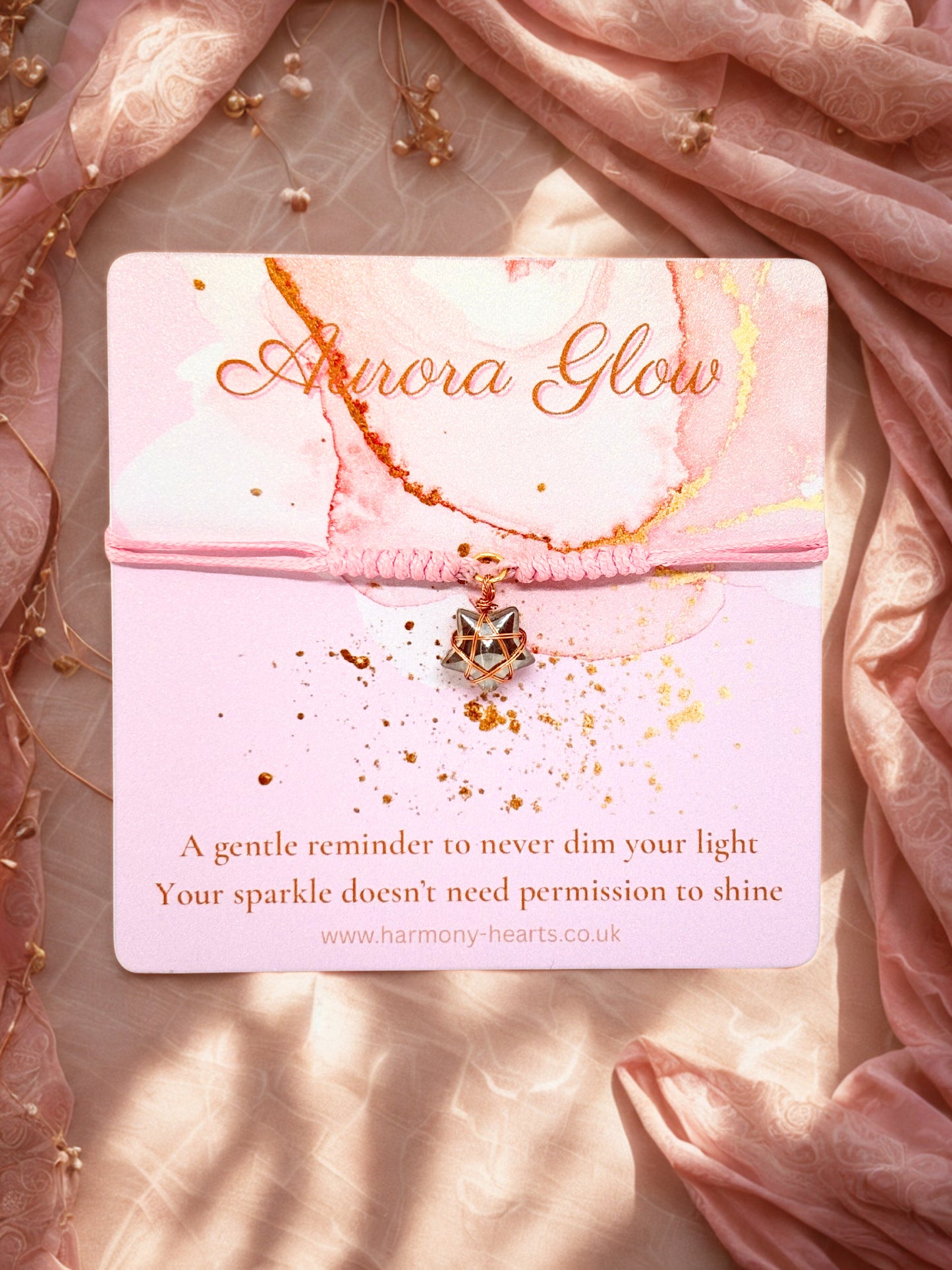 Pink cord bracelet with a glass heart charm on a Harmony Hearts branded card titled Aurora Glow