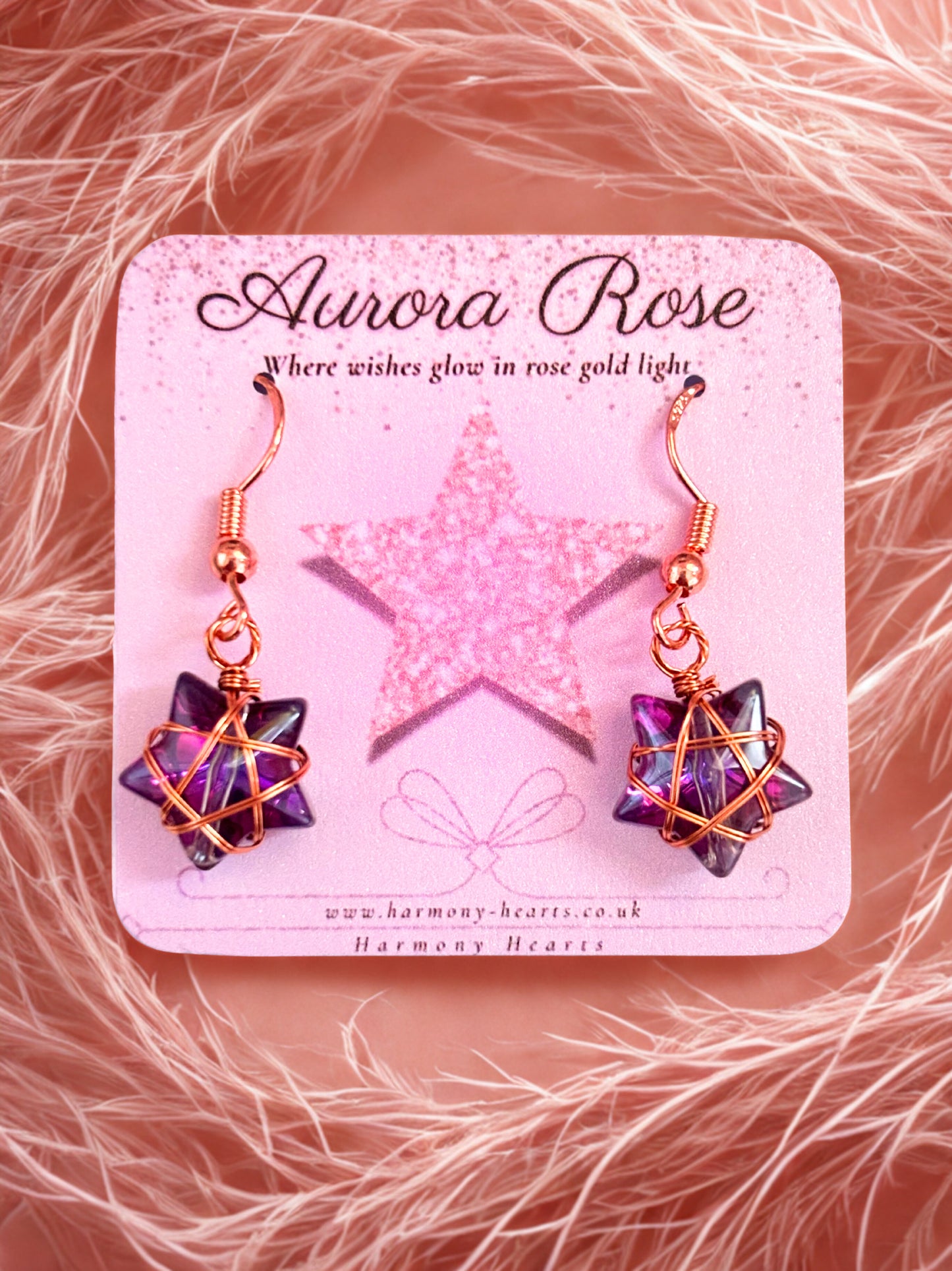 Star-shaped earrings on a 'Aurora Rose' branded card with a pink star design.