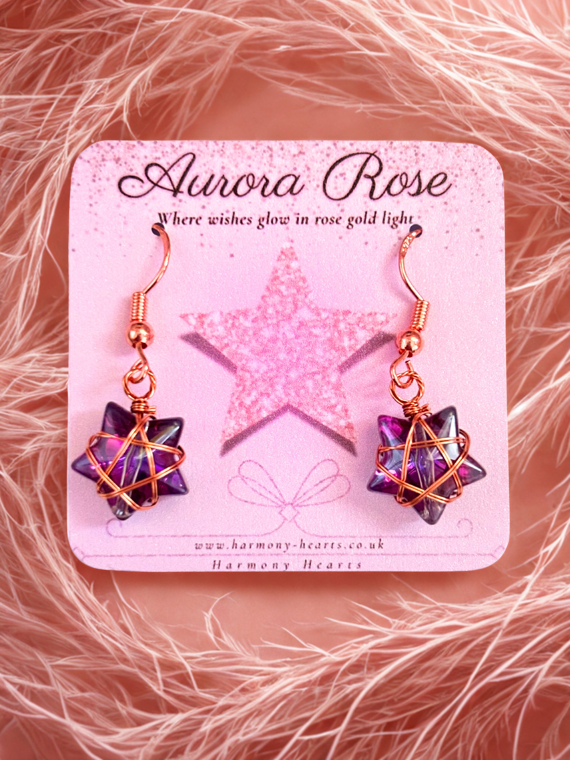 Star-shaped earrings on a 'Aurora Rose' branded card with a pink star design.