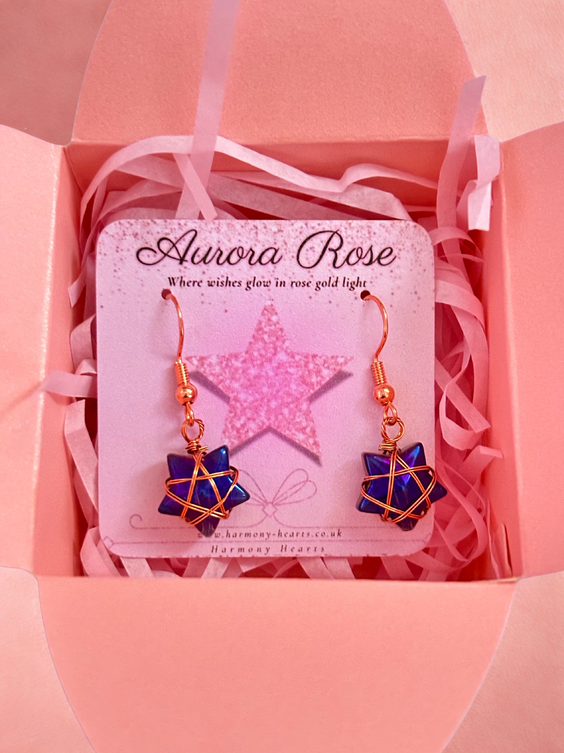 Aurora Rose earrings with blue and gold design in a pink box