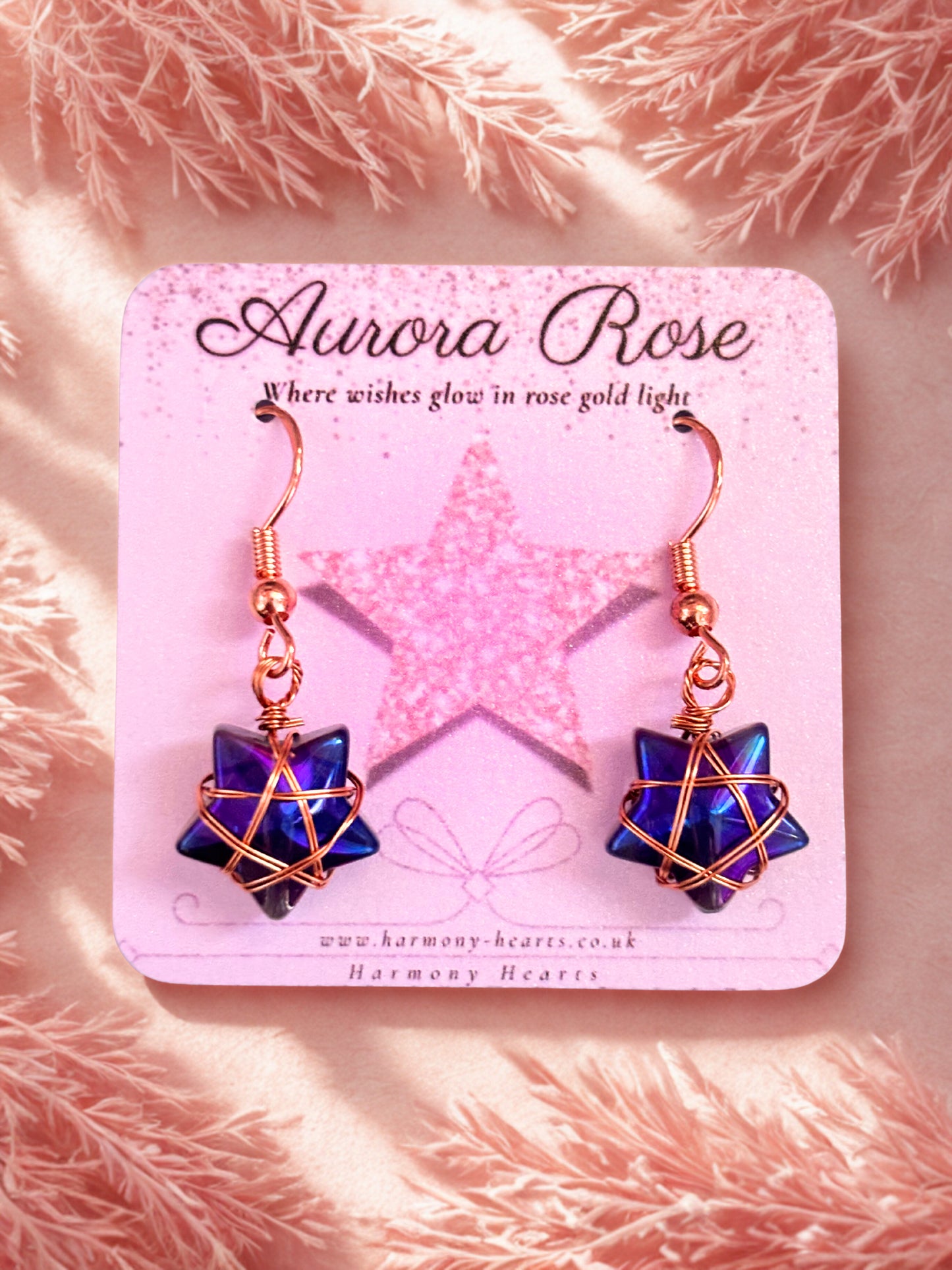 Pair of earrings on a 'Aurora Rose' branded card with a pink background.