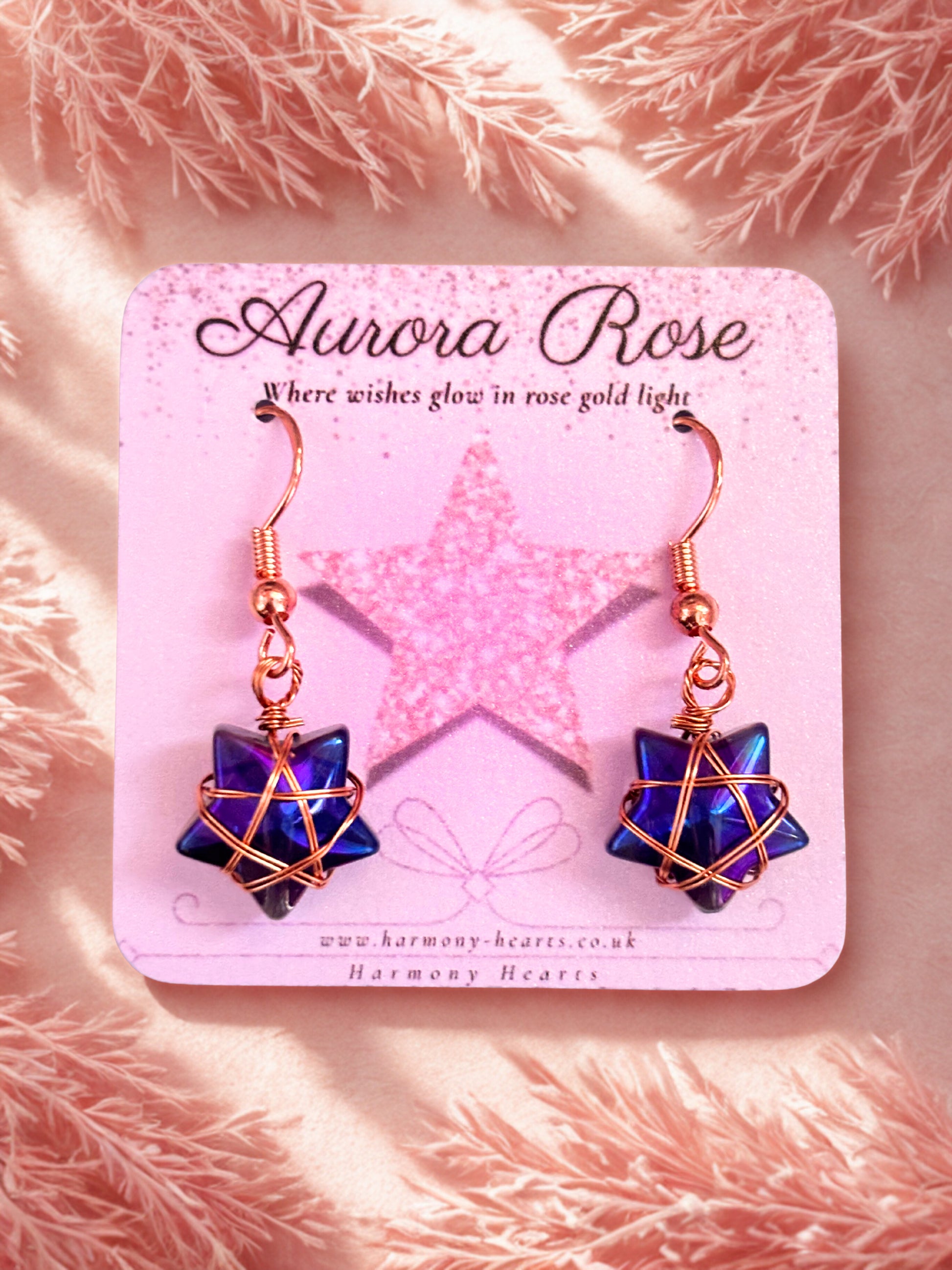 Pair of earrings on a 'Aurora Rose' branded card with a pink background.