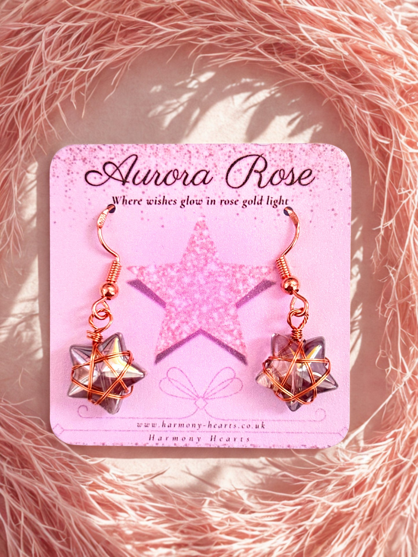 Aurora Rose earrings on a pink card with a star design, set against a pink textured background.