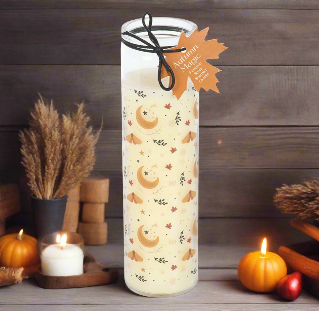 Decorative candle with autumn design and leaf tag on a wooden surface with pumpkins and candles.