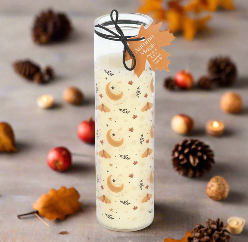 Decorative candle with autumn-themed design on a surface with fall elements like leaves and pinecones.