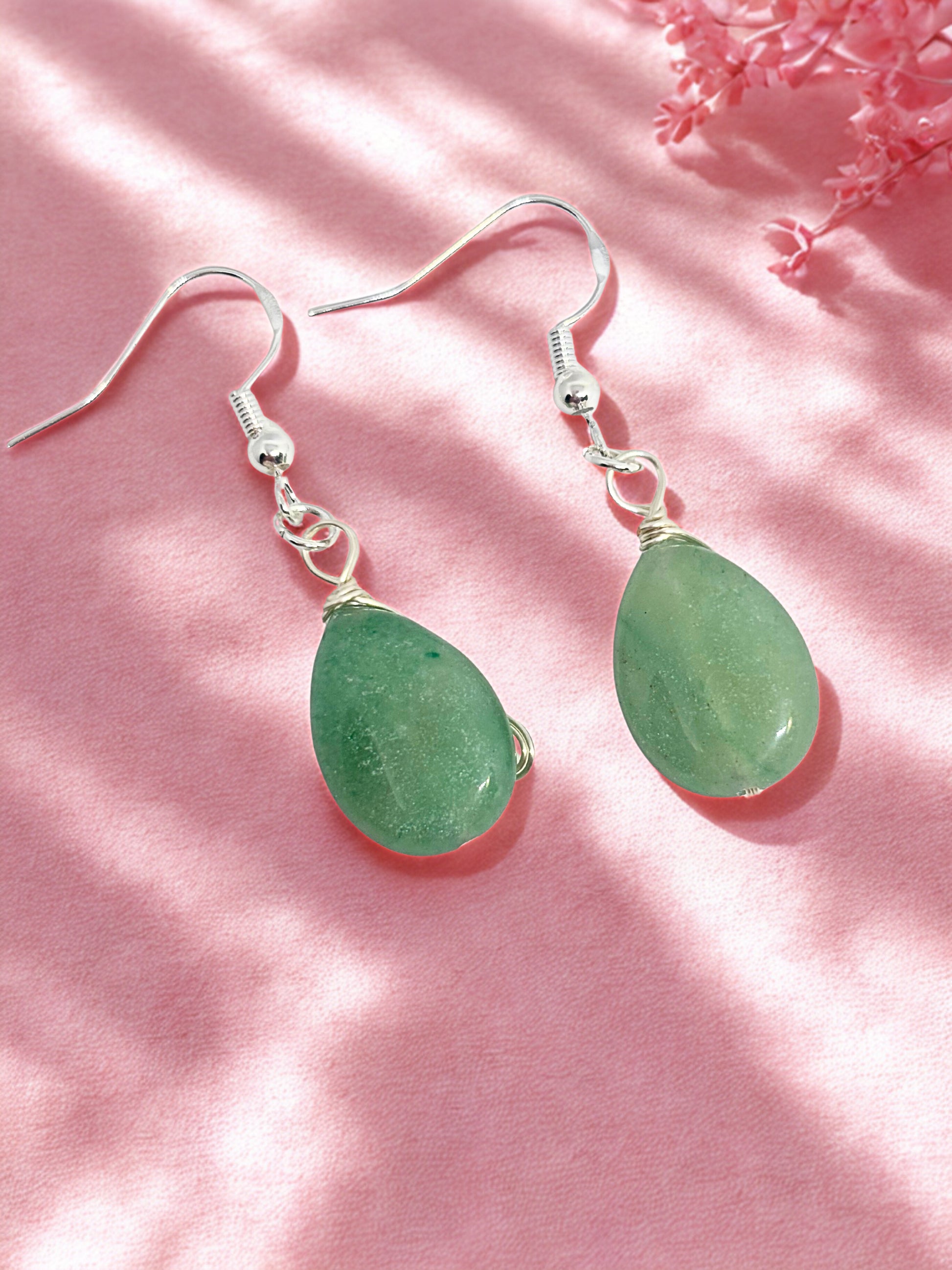 Green aventurine teardrop earrings on a pink background