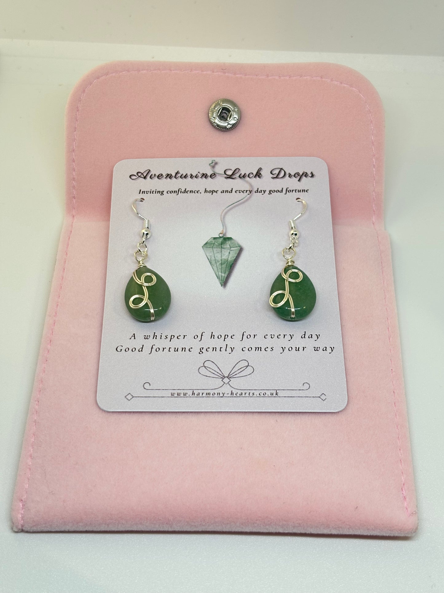 Green teardrop earrings on a pink card with text
