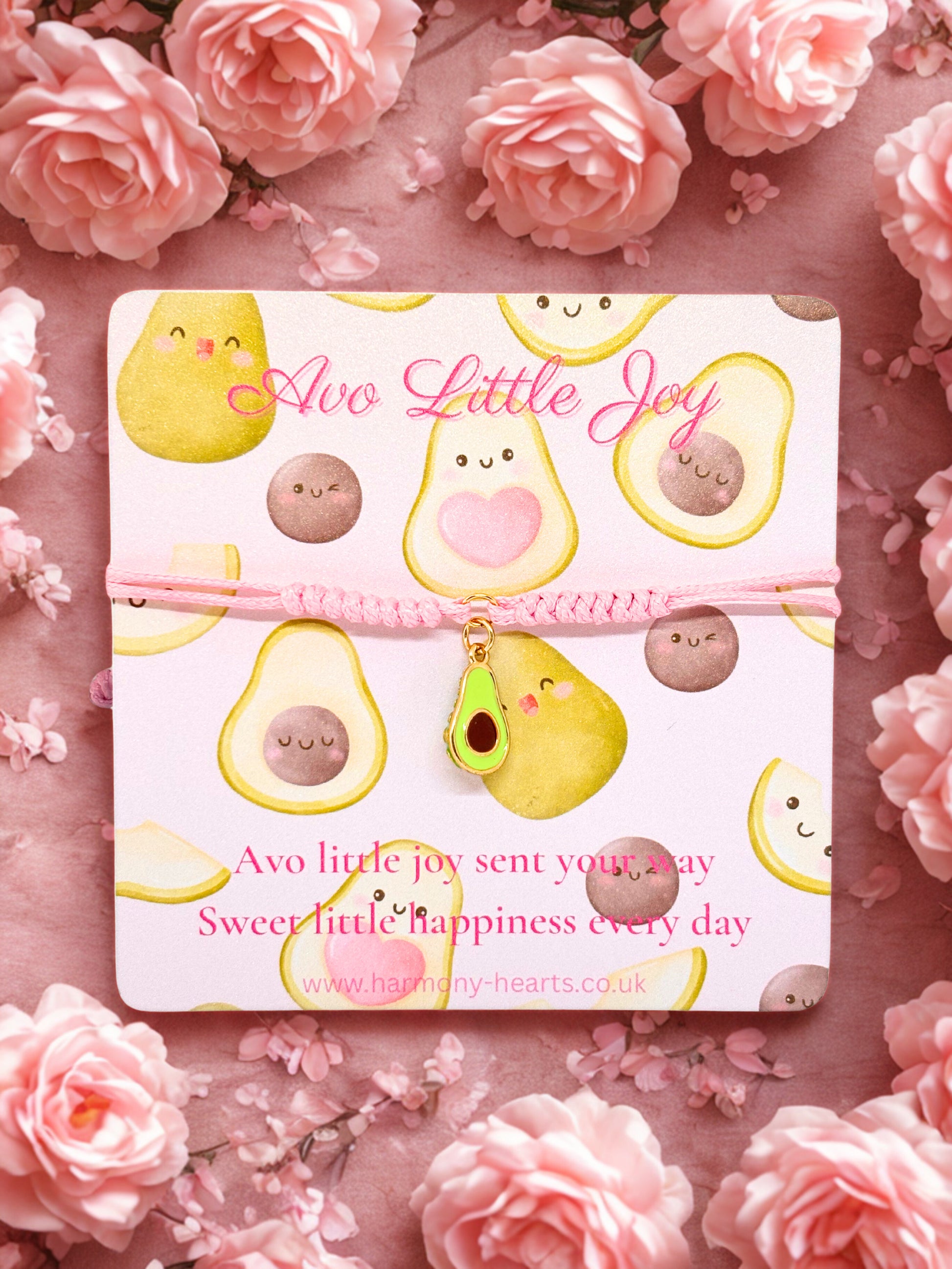 Pink cord bracelet with avocado charm on a branded card with avocado designs on a pink floral background