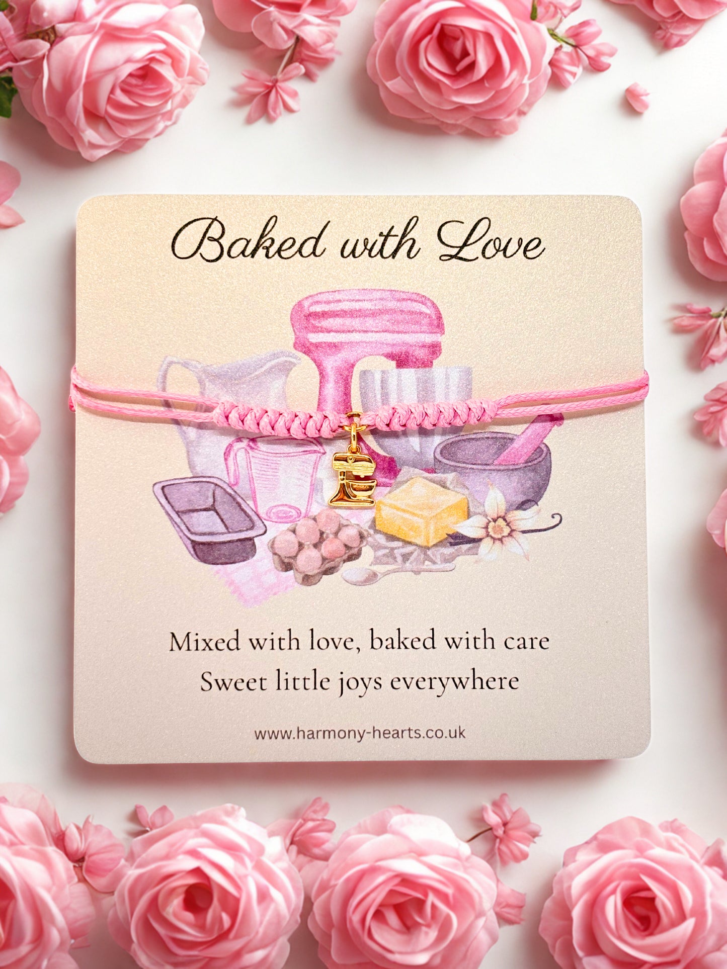 Branded card with 'Baked with Love' text and illustrations with  a gold mixer charm bracelet surrounded by pink roses.