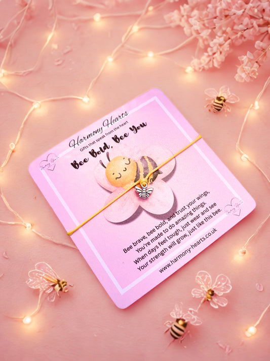 Bee Bracelet on a Pink card with a bee and flower design on a pink background with fairy lights and flowers.